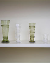 Styled image featuring the Bollenglass Design Clear Petite Spiral Tumbler, Green Petite Spiral Tumbler, Clear Small Spiral Tumbler and Clear Liquor Glass.