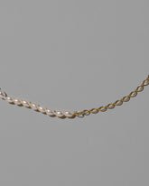 Closeup details of the Half Oval Chain & White Seed Pearl Necklace on light color background.