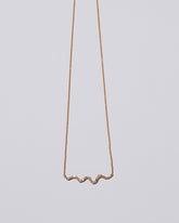Closeup detail of the White Diamond Ripple Wave Necklace on light color background.