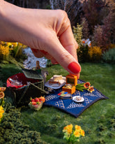 Styled image of the California Poppy Charm, with the Daffodil Charm, Luna Ring Charm, Stick of Salted Butter Charm, Sardine Can Charm, Sardine Fish Charm, Saltine Charm and Caviar Charm.