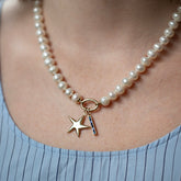 product_details::Gold Pearl Openable Link Necklace, Gold Large Verve Five Point Star Charm and Sapphire Identity Charm on model.