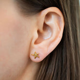 product_details::Gold Verve Five Point Star Stud Earrings on model.