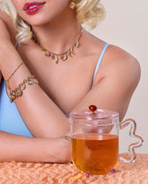 Styled image featuring the Twisted Chain Bracelet, Short Loop Chain Necklace and Endless Clasp Bracelet styled with the Wild Strawberry Charm, Bruised Banana Charm, Waffle Charm, Orange Slice Charm, Bacon Charm, Nine Sunny Side Up Egg Charm, Ruby Pavé Strawberry Charm, Croissant Charm, Avocado Toast Charm, Button Mushroom Charm, Strawberry Charm, Peeled Banana Charm and Melon Slice Charm on model.