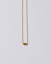 Gold Altered State Necklace on light color background.
