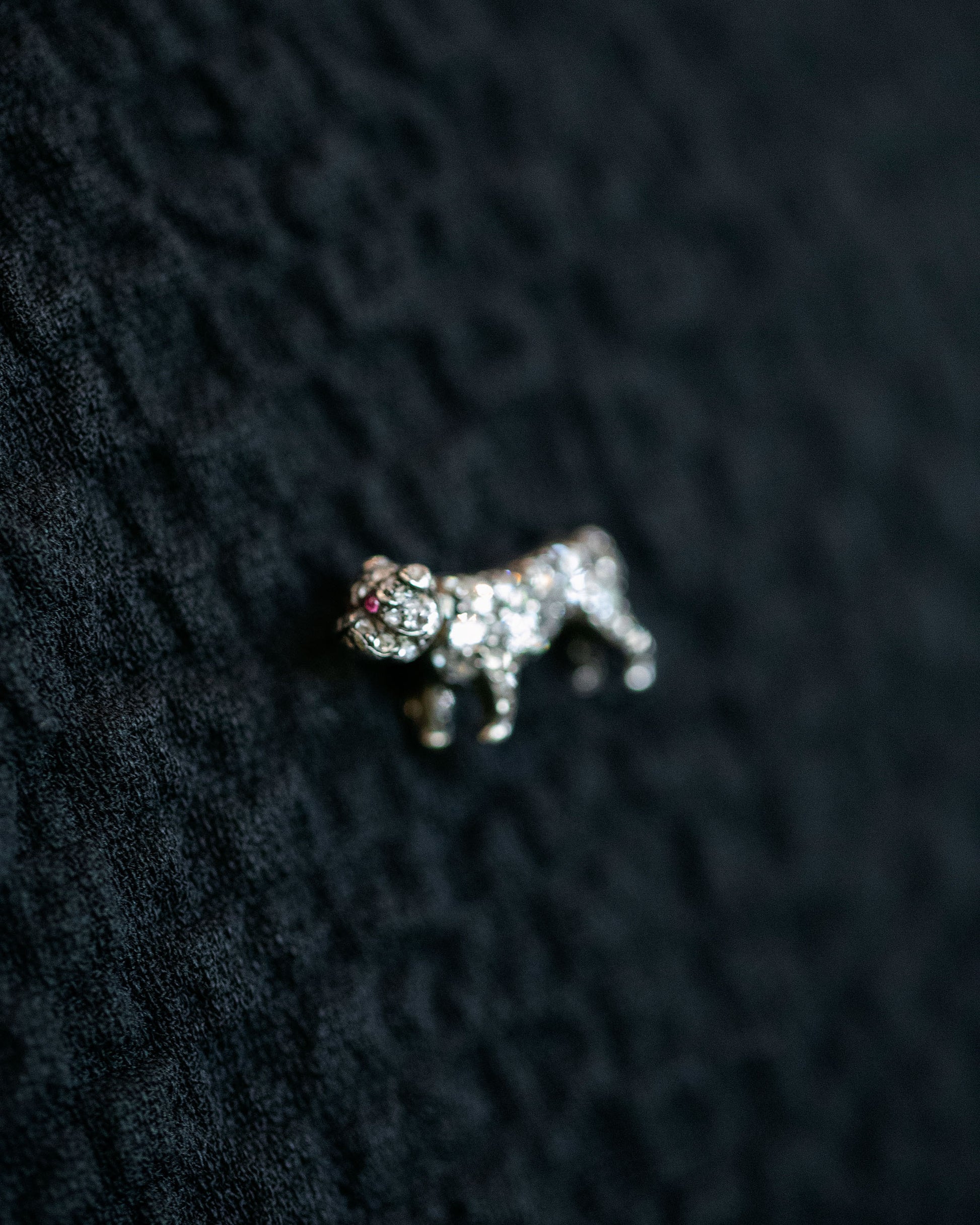 Closeup details of the Antique Diamond & Ruby-Eyed English Bulldog Brooch on dark color background.