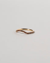 View from the side of the Gold Garnet Pavé Mini Curve Band on light color background.