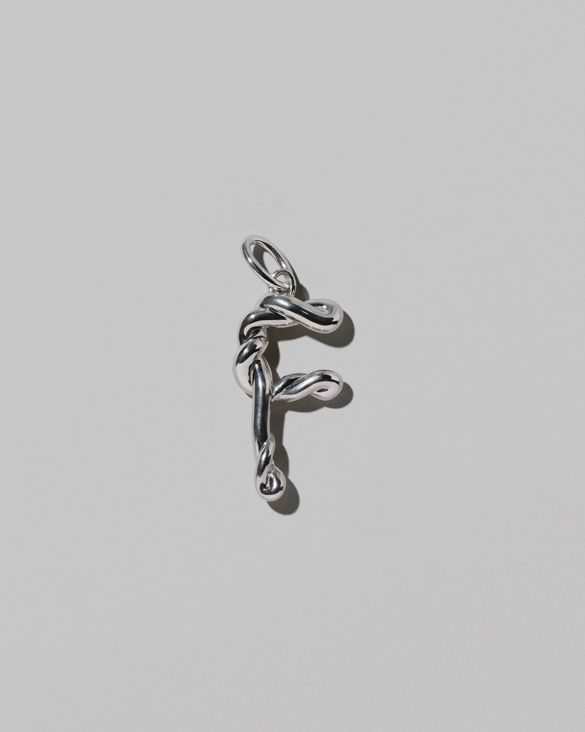 CRZM Sterling Silver Letter F Bag Charm on light color background.