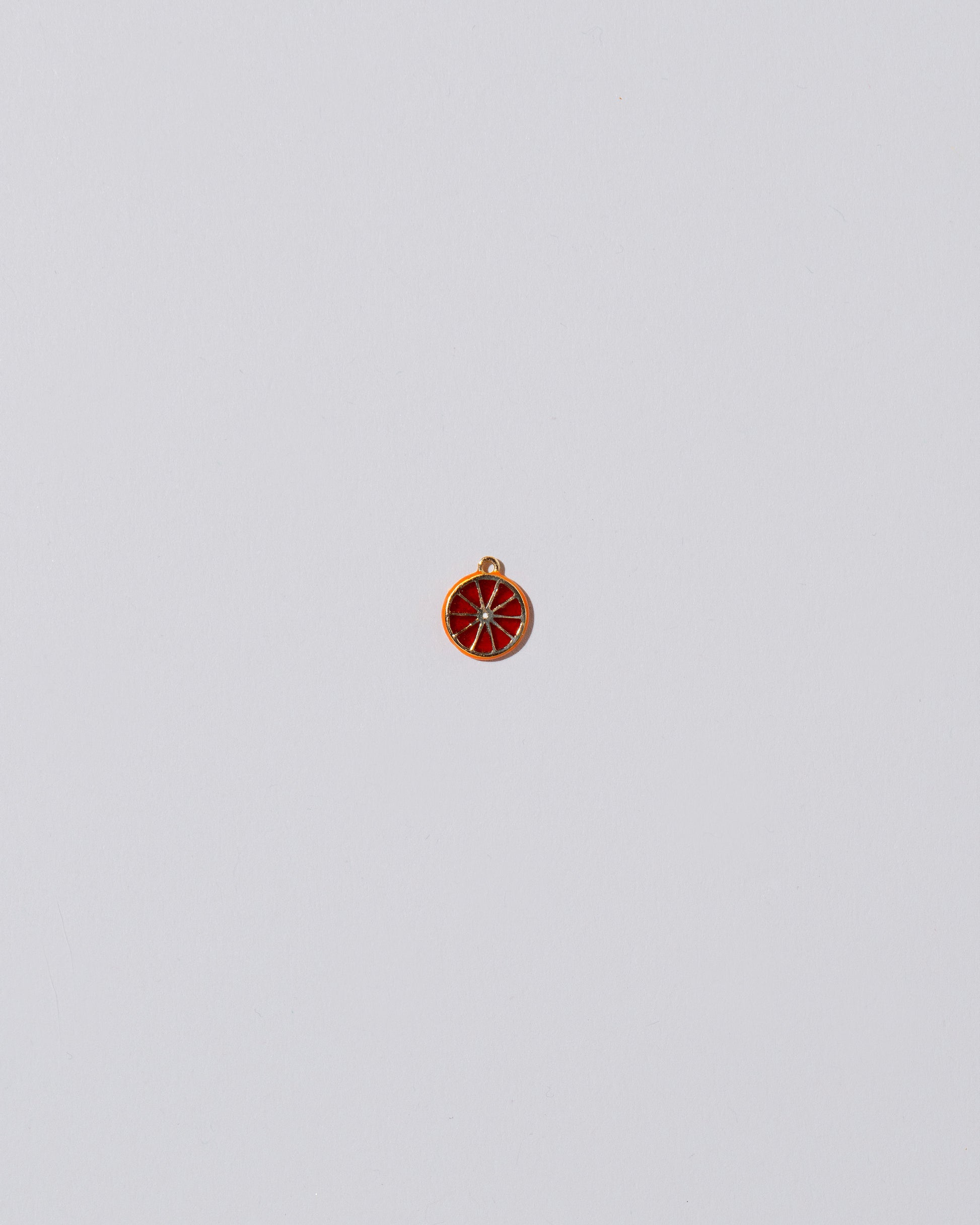 Small Tangerine Slice Charm on light color background.