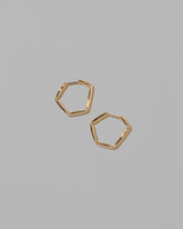 Gold Crimp Hoop Earrings on light color background.