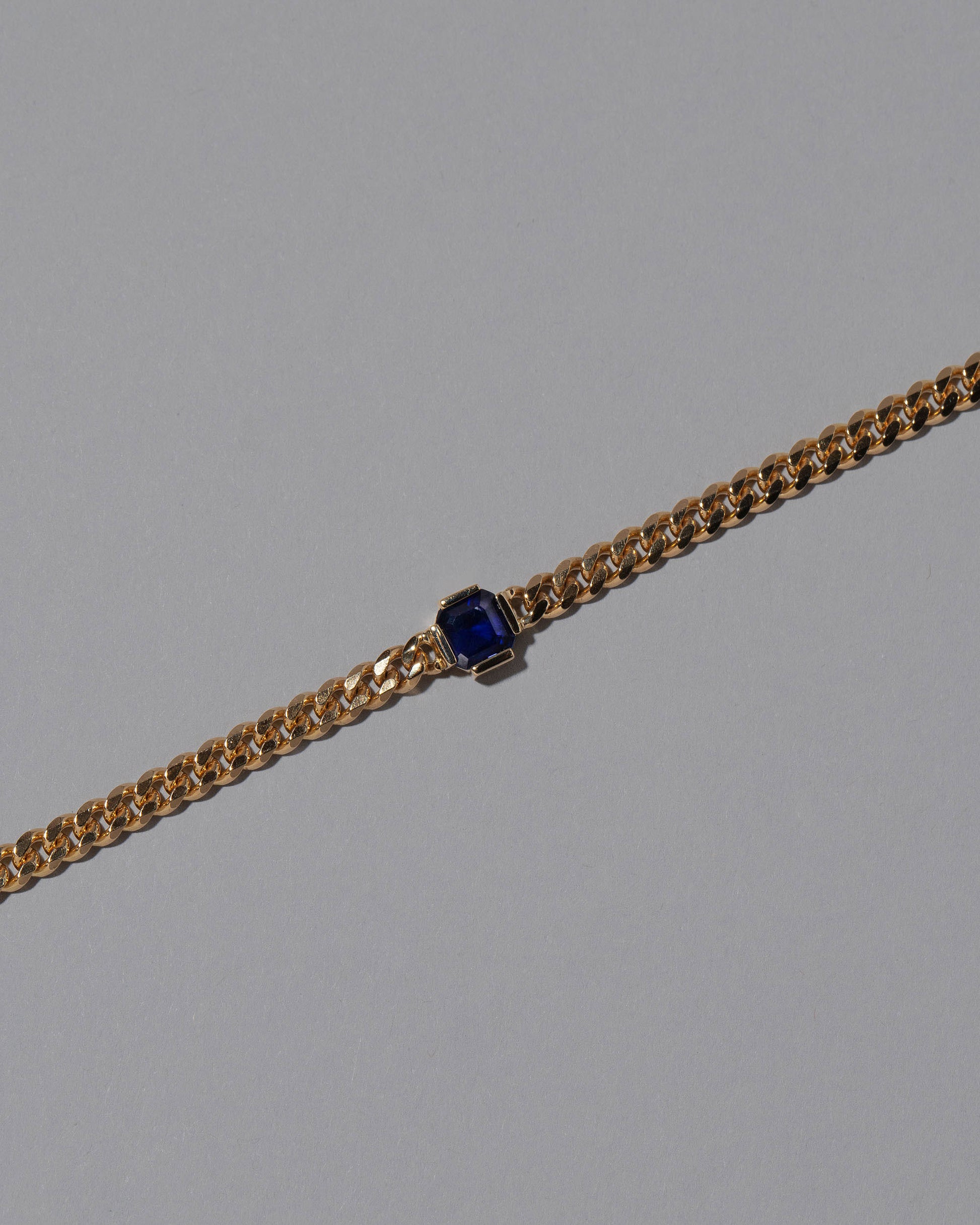 Closeup details of the Blue Sapphire Fold Necklace on grey color background.
