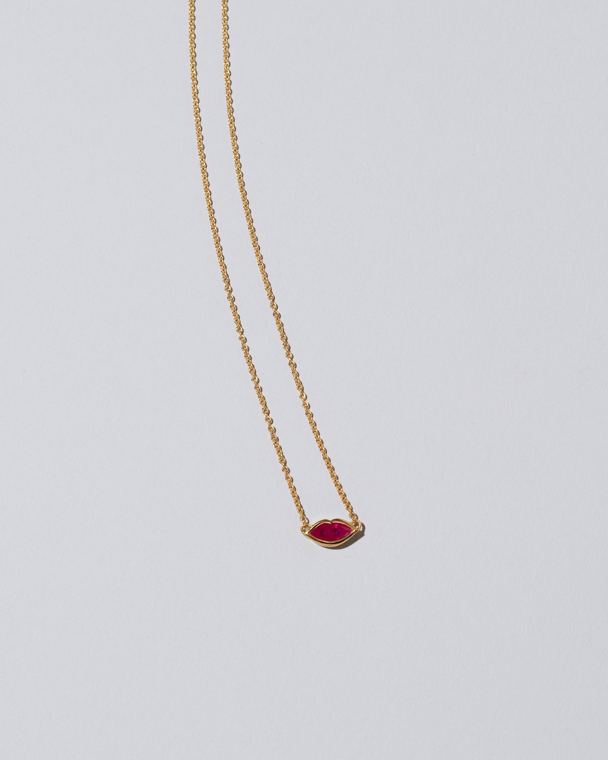 Closeup detail of the Red Big Kiss Necklace on light color background.