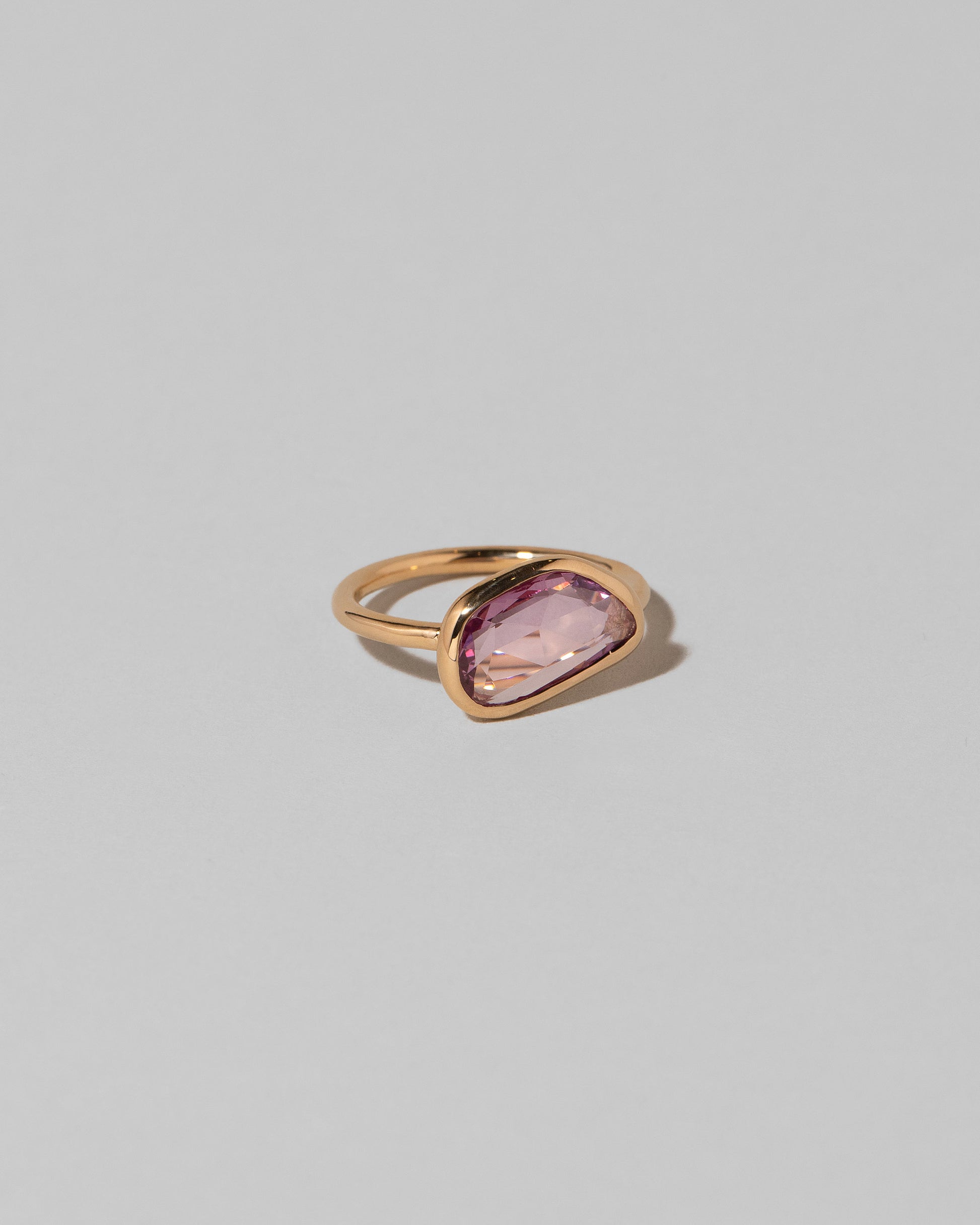 View from the side of the Gusher Pink Sapphire Ring 011 on light color background.