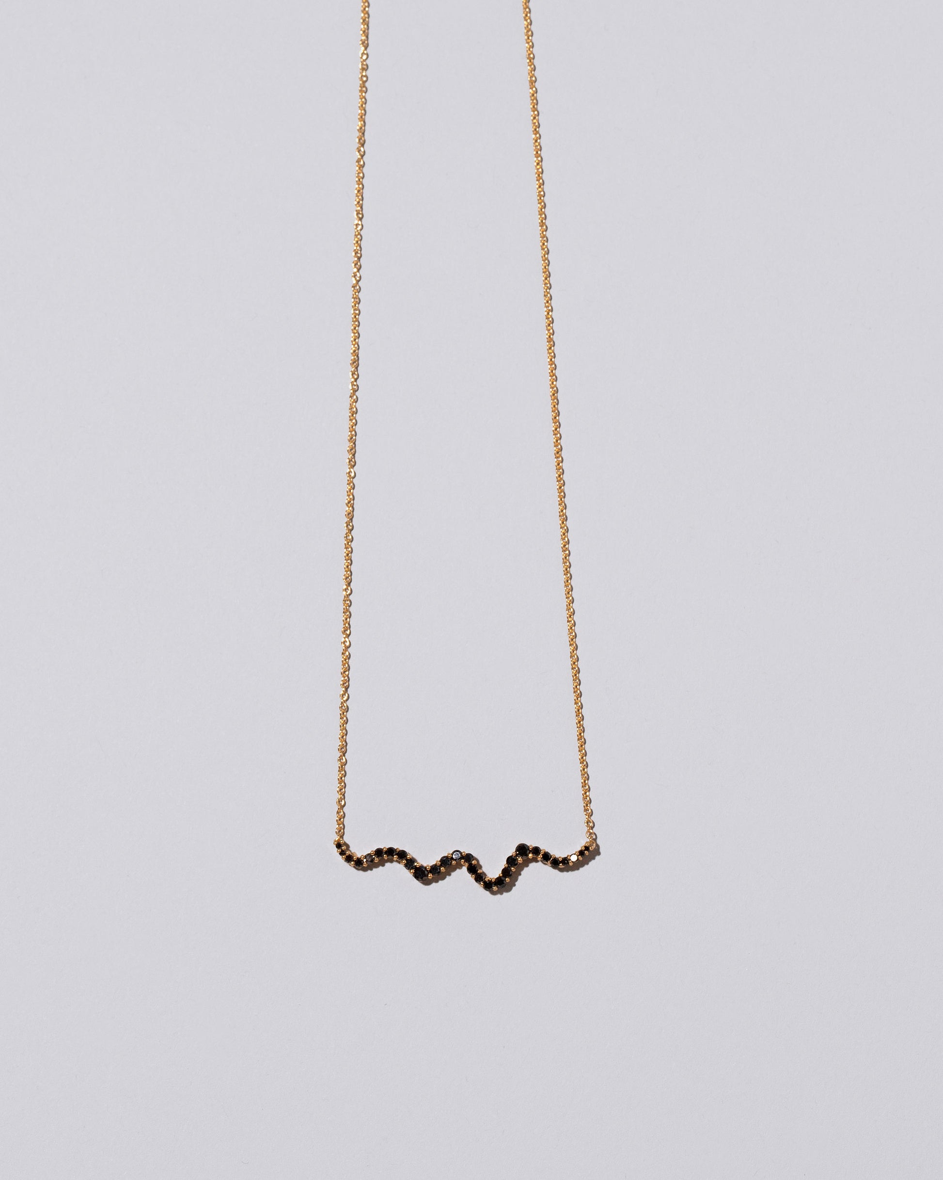 Closeup detail of the Black Diamond Ripple Wave Necklace on light color background.