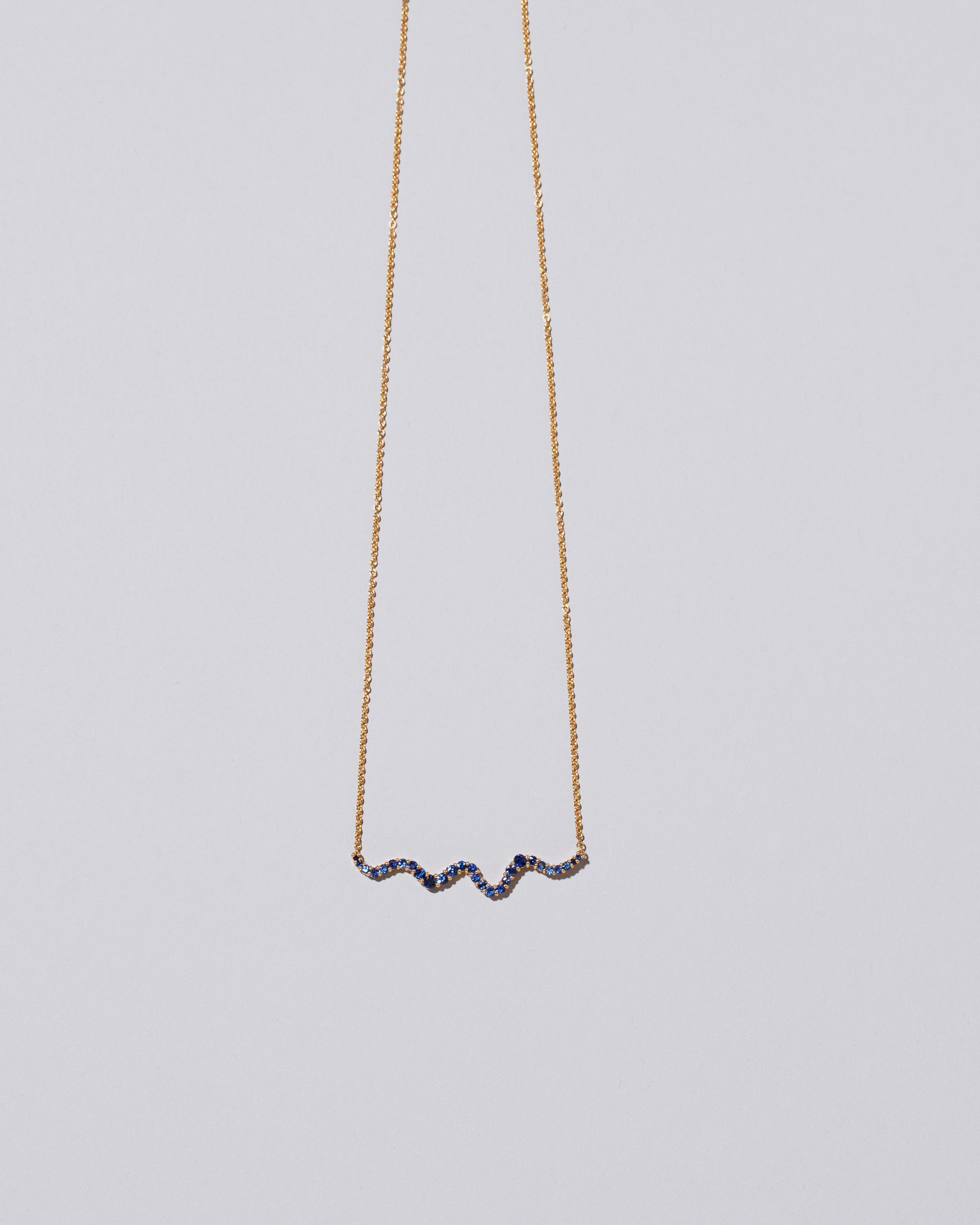 Closeup detail of the Blue Sapphire Ripple Wave Necklace on light color background.