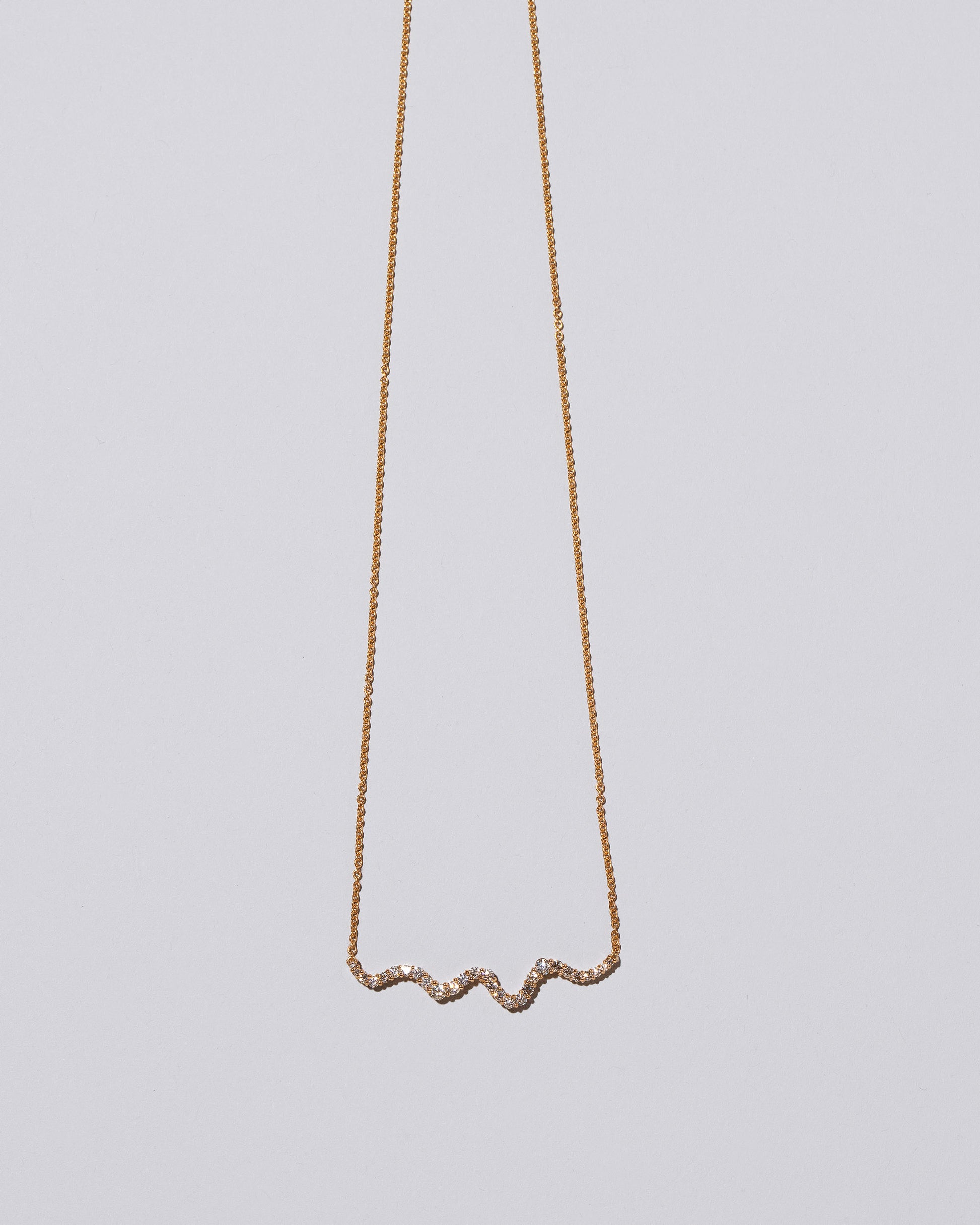 Closeup detail of the White Diamond Ripple Wave Necklace on light color background.