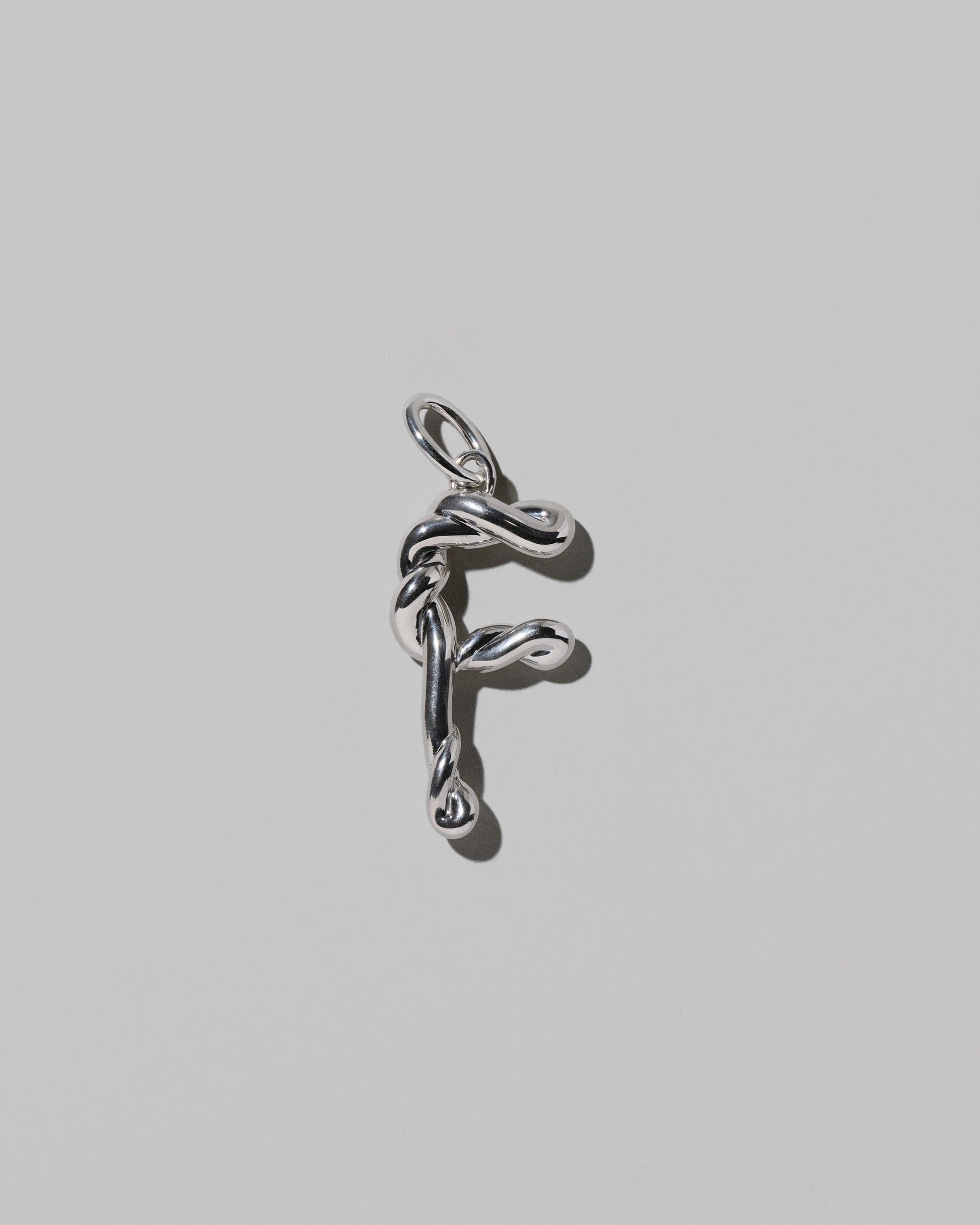 CRZM Large Letter F Charm set in sterling silver on light color background.