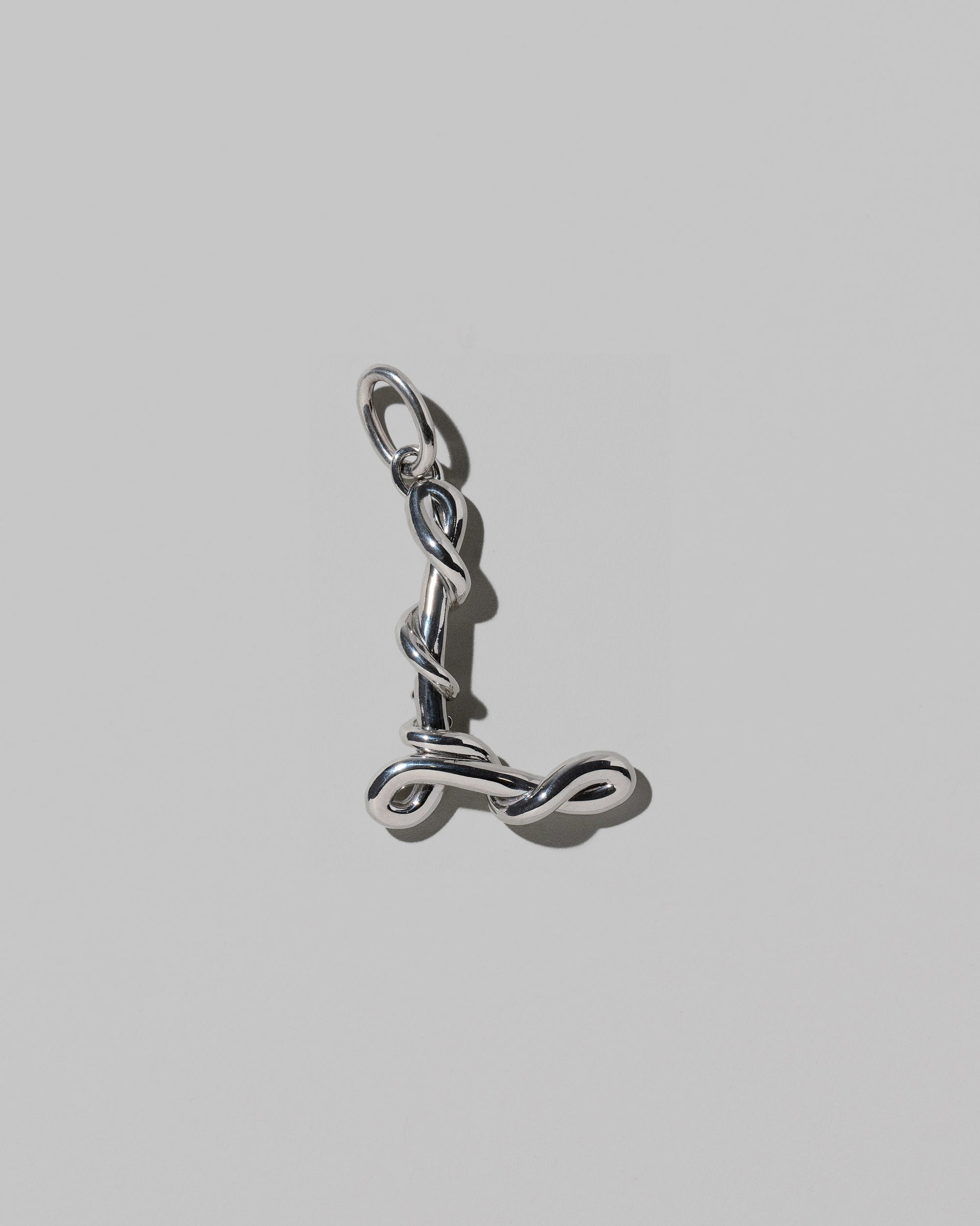 CRZM Large Letter L Charm set in sterling silver on light color background.