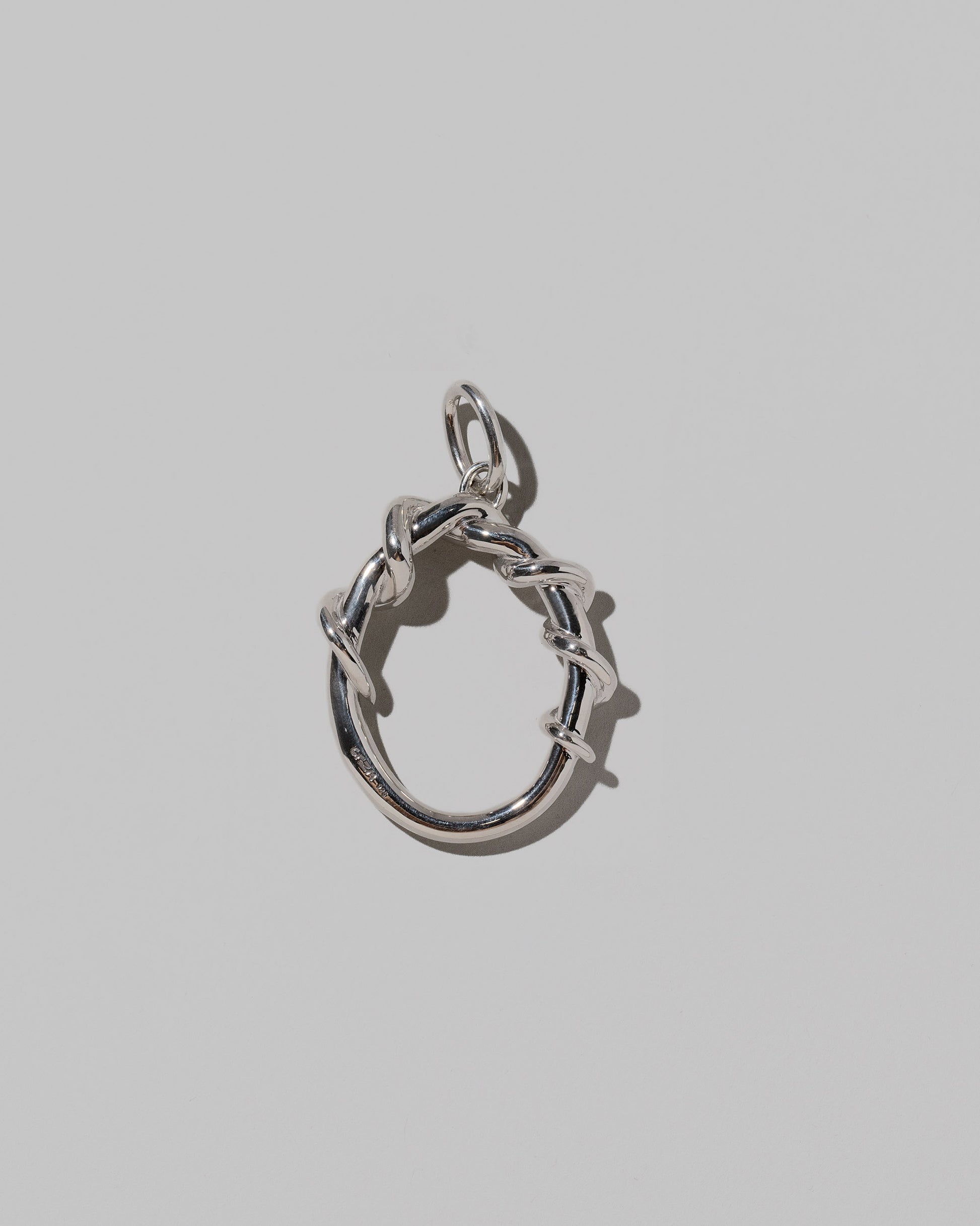 CRZM Large Letter O Charm set in sterling silver on light color background.