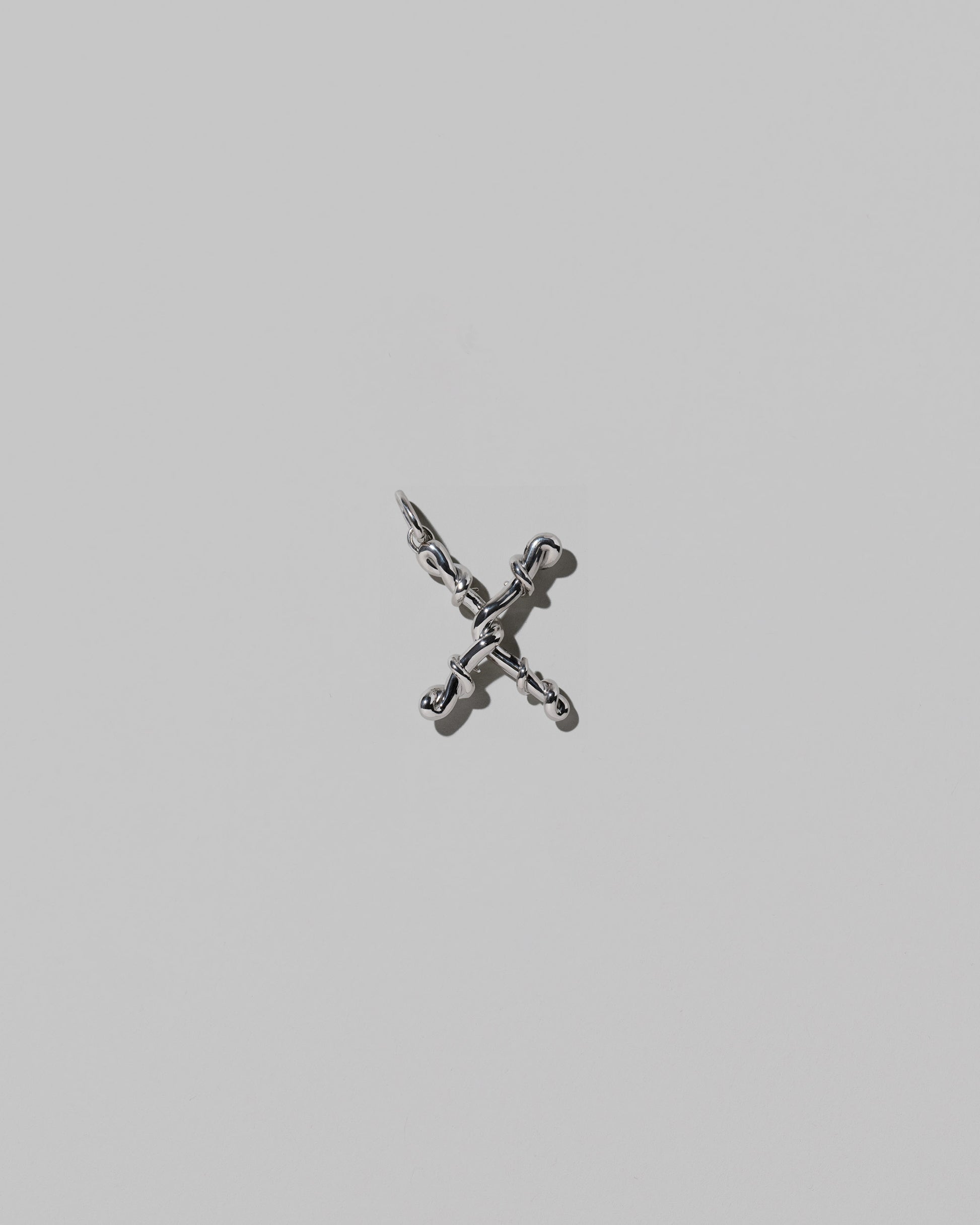 CRZM Medium Letter X Charm set in sterling silver on light color background.
