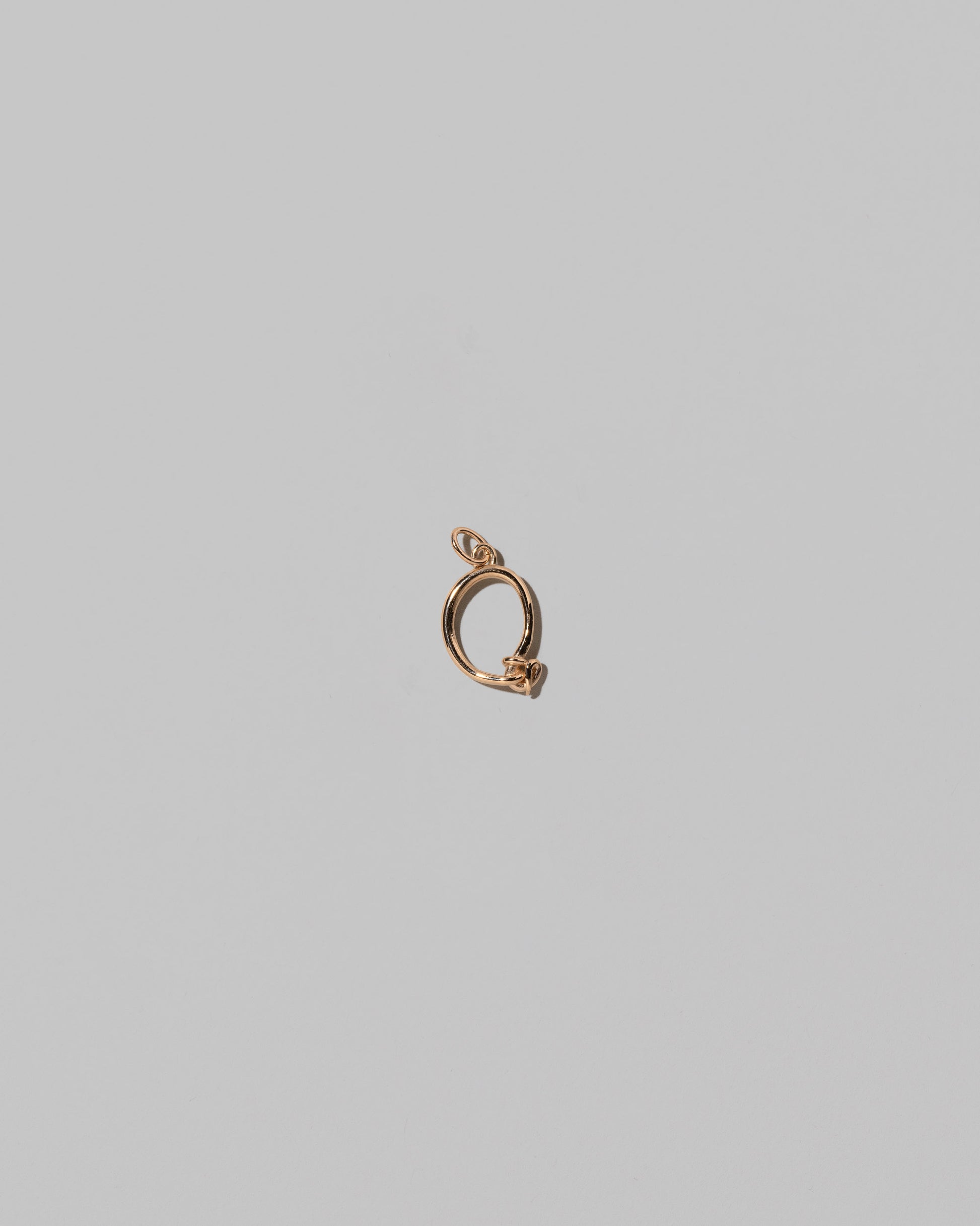 CRZM Mini Letter Q set in solid gold on light color background.