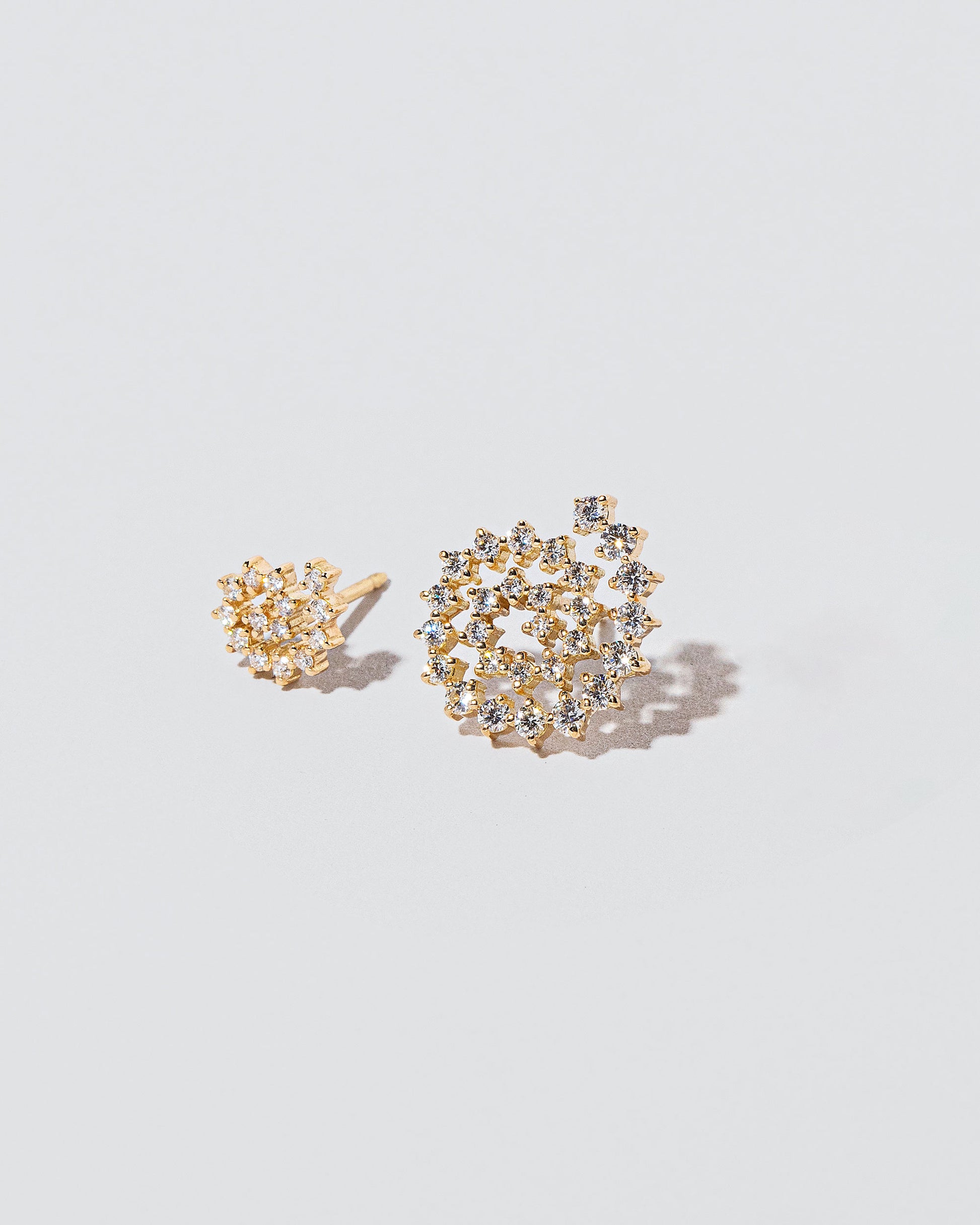 Mini and Full White Diamond Left Spiral Stud Earring Singles on light color background.
