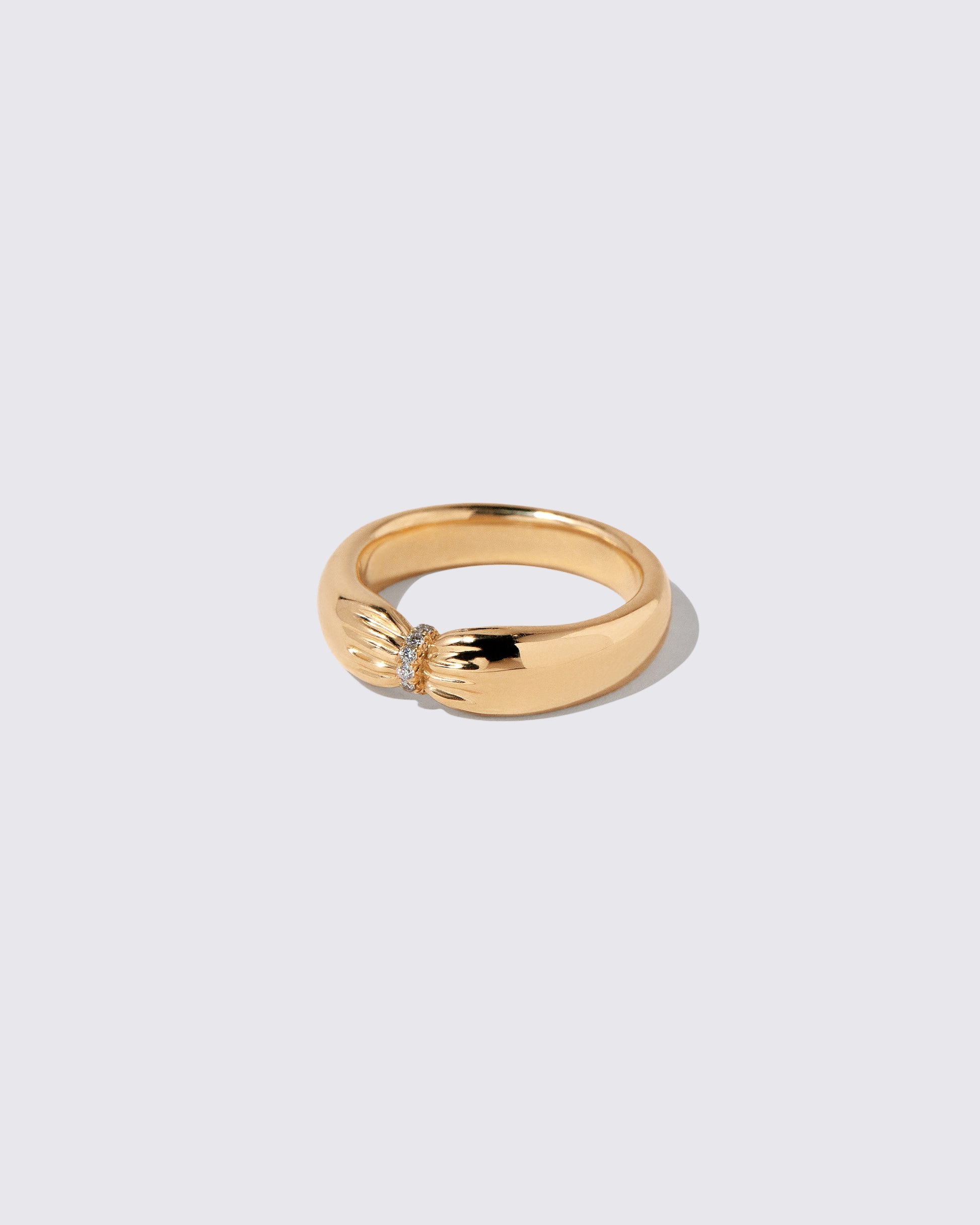 View from the side of the Gold Pavé Pinch Band on light color background.