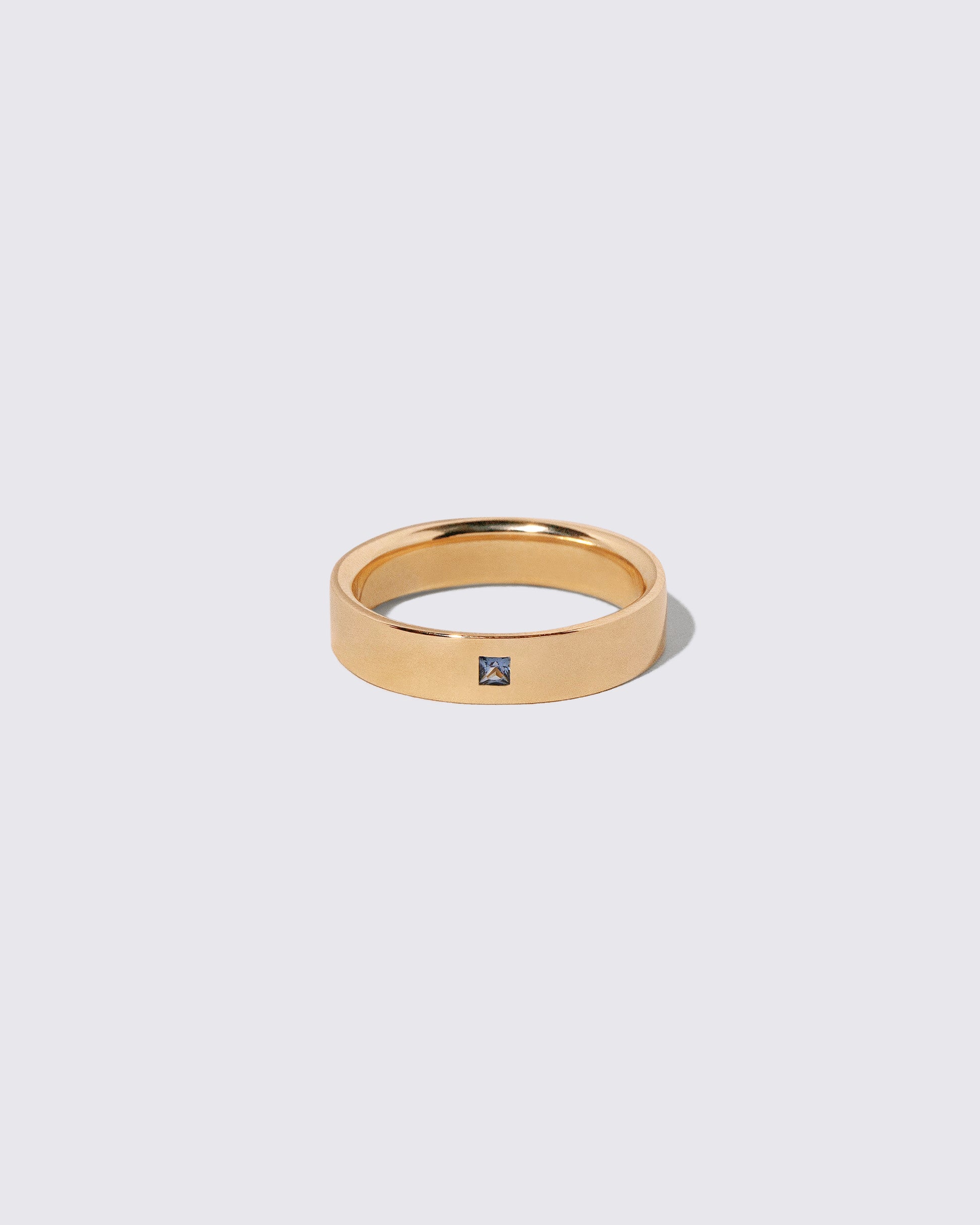 Gold Yogo Mine Cornflower Blue Sapphire 5mm Square Cut Piet Band on light color background.