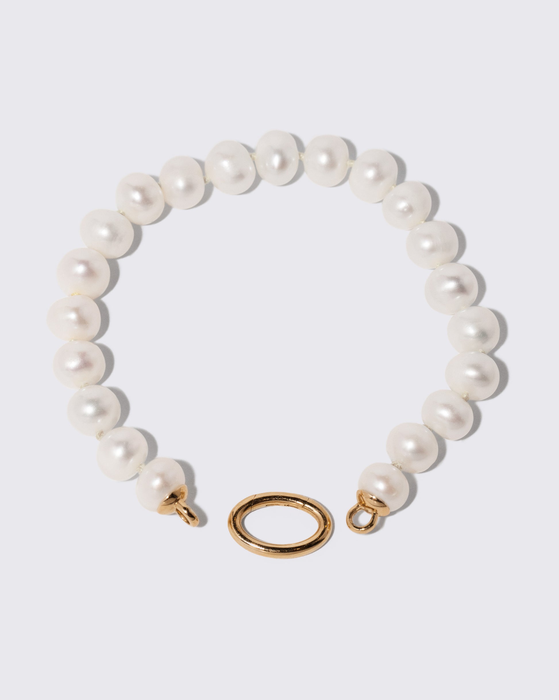 Detail view of the detachable Mociun Long Oval Openable Link closure on the Gold Pearl Openable Link Necklace on light color background.