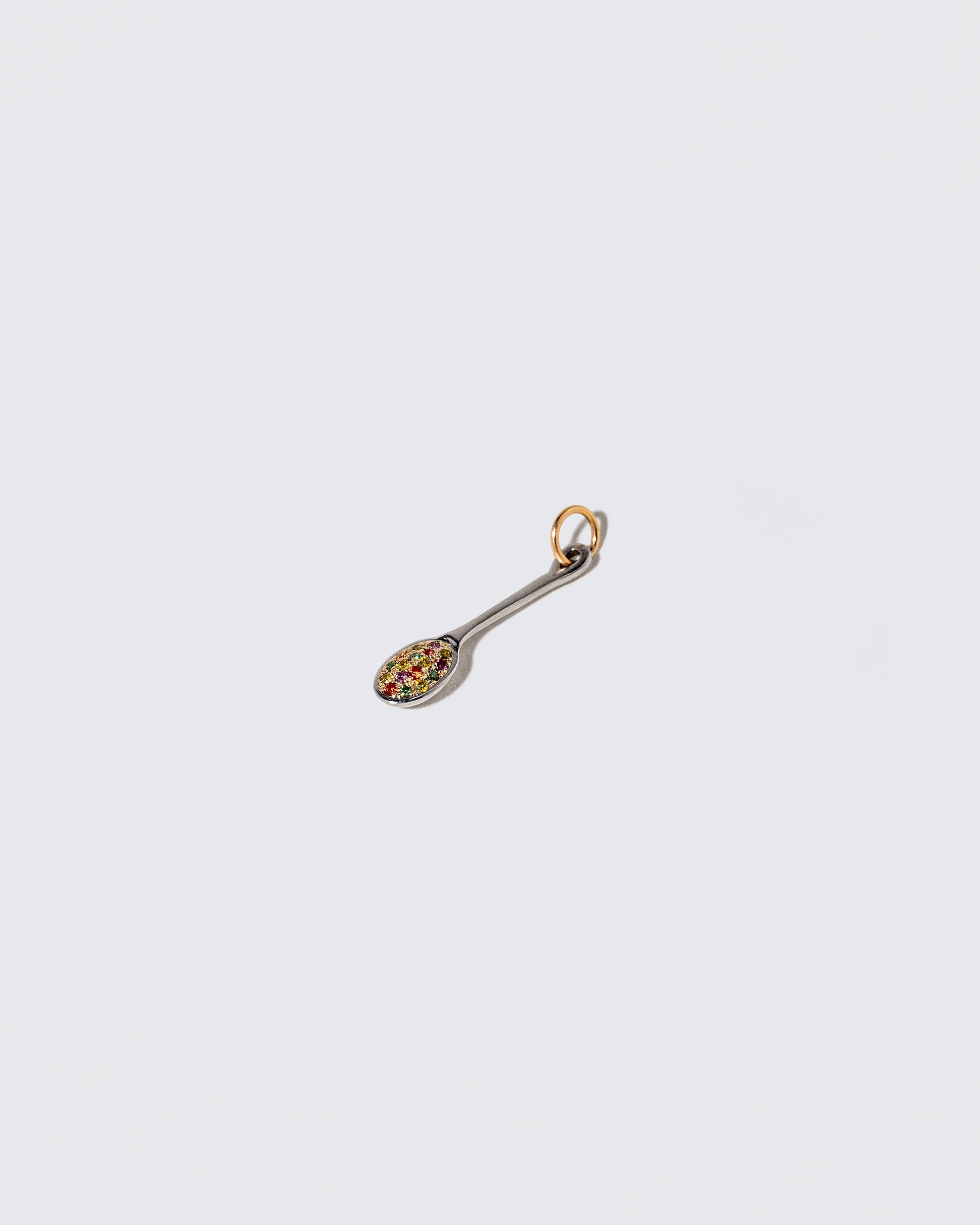 View from the side of the Cereal Spoon Charm on light color background.