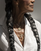Styled image on model featuring the Yellow Sapphire Gusher Charm Huggie Hoop Earrings, Link Necklace, an Accumulation Necklace paired with the Grand Duality Medallion Pendant, and a Gold Oval Openable Link added to the Gold Butter Chain Necklace that holds a Birthstone Pearl Pendant, Peach Charm, Small Round Memento Pendant, Harmony Pendant and Diamond Poise Charm.