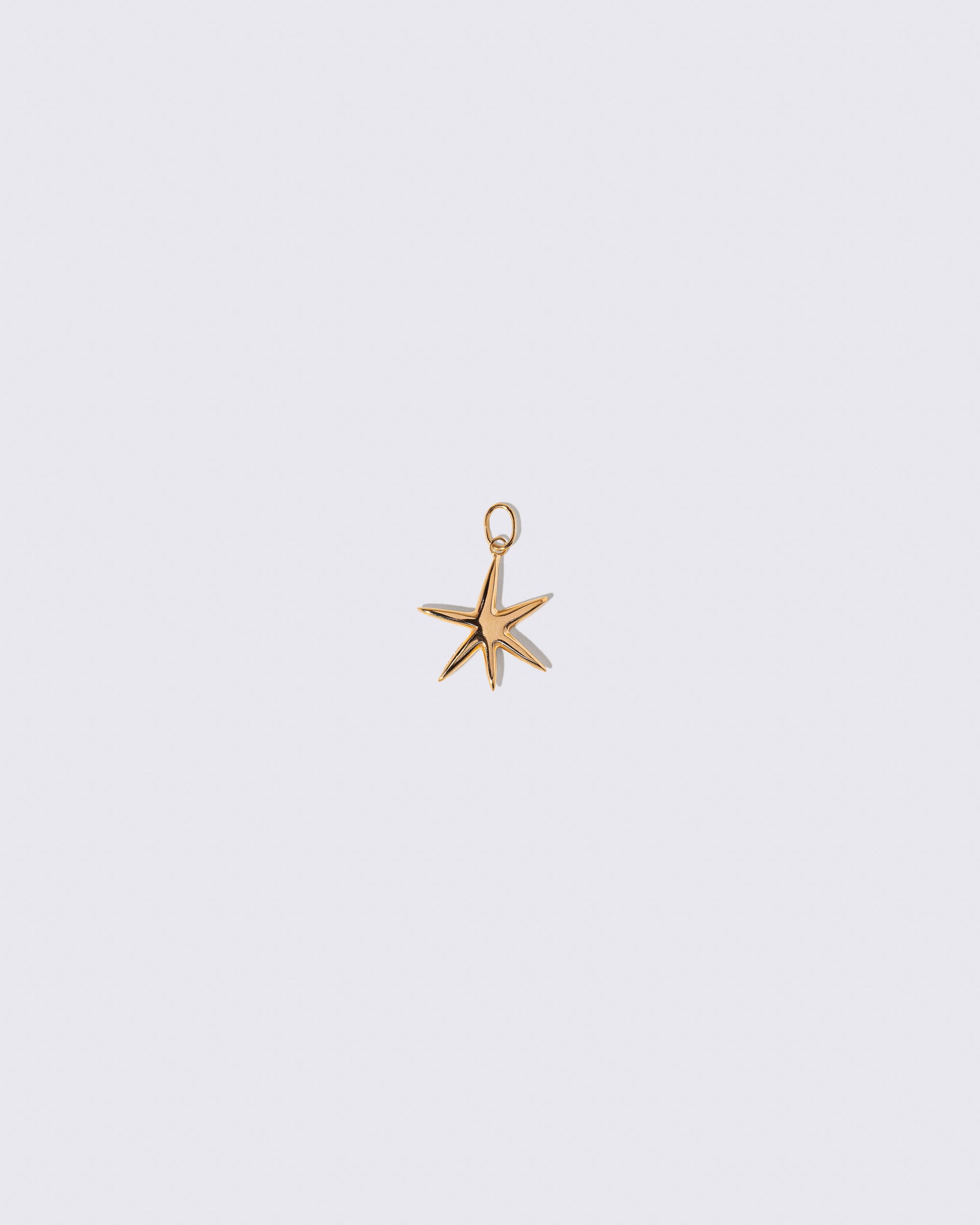 Gold Grand Verve Six Point Star Charm on light color background.