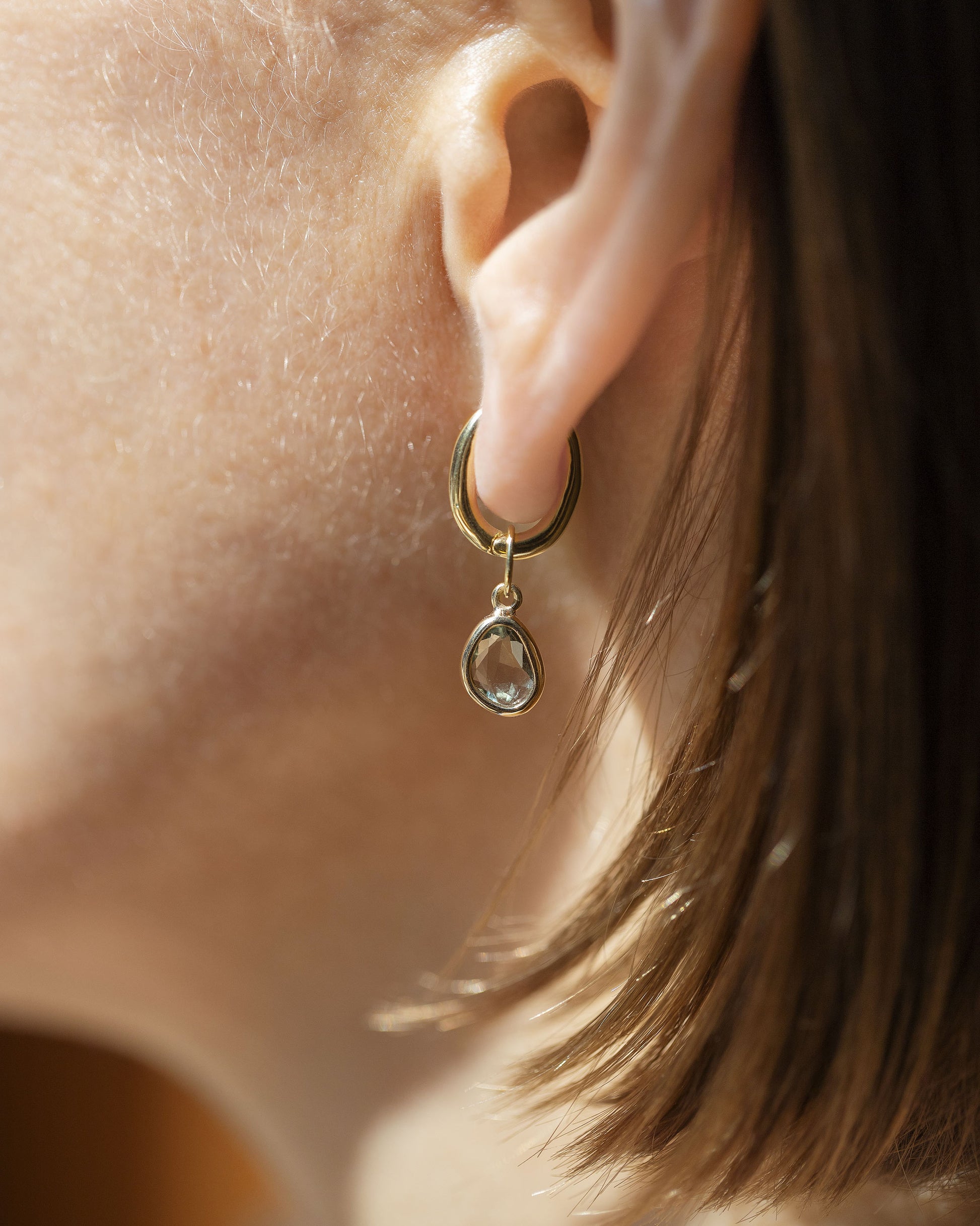 Styling Huggie Hoop Earring Single and Green Sapphire Gusher Charm on model.