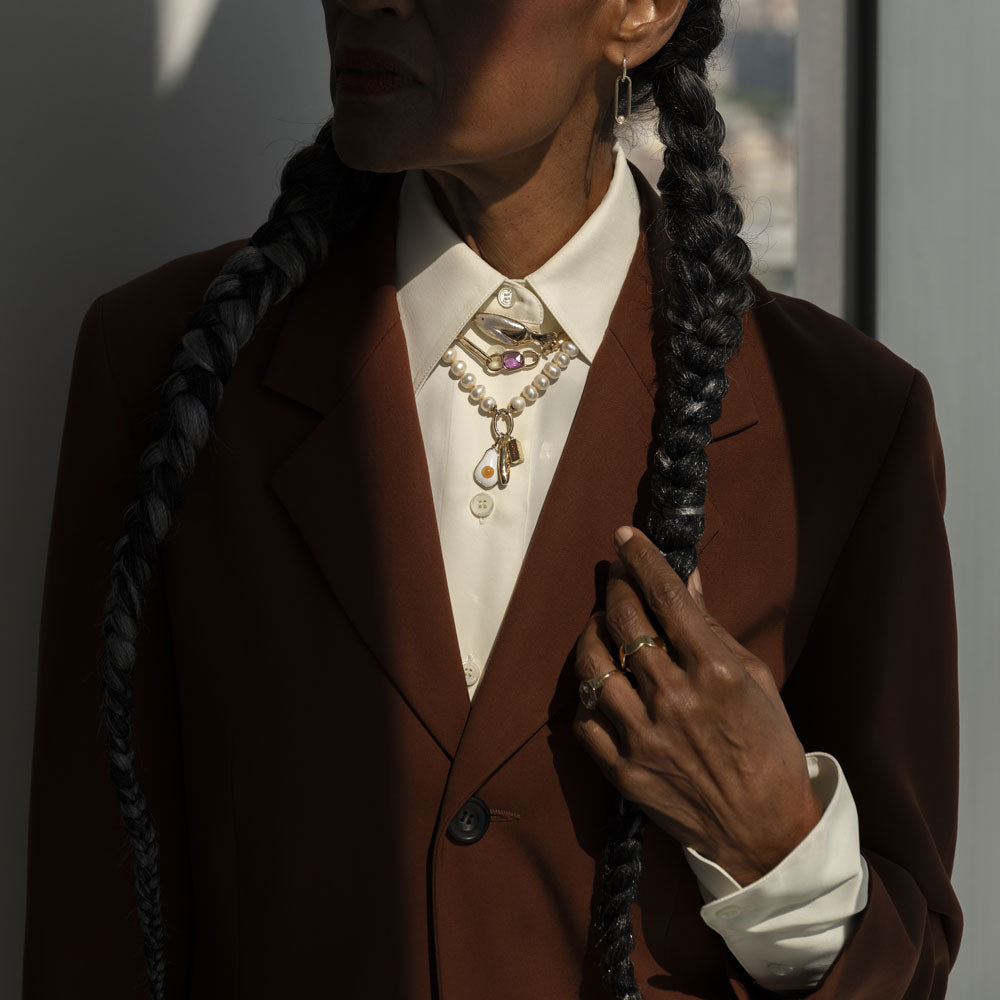 product_details::Styled image on model featuring the Gold 5mm Ripple Band, Pearl Link Huggie Hoop Earrings, the Frank Fish Brooch pinned on the collar above the Sapphire Gusher Openable Pendant on Link Necklace, and on clasp of the Gold Pearl Openable Link Necklace is a Demi Baguette Charm, Stick of Salted Butter Charm and Fried Egg Pendant.