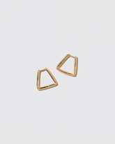 Gold Bend Hoop Earrings on light color background.