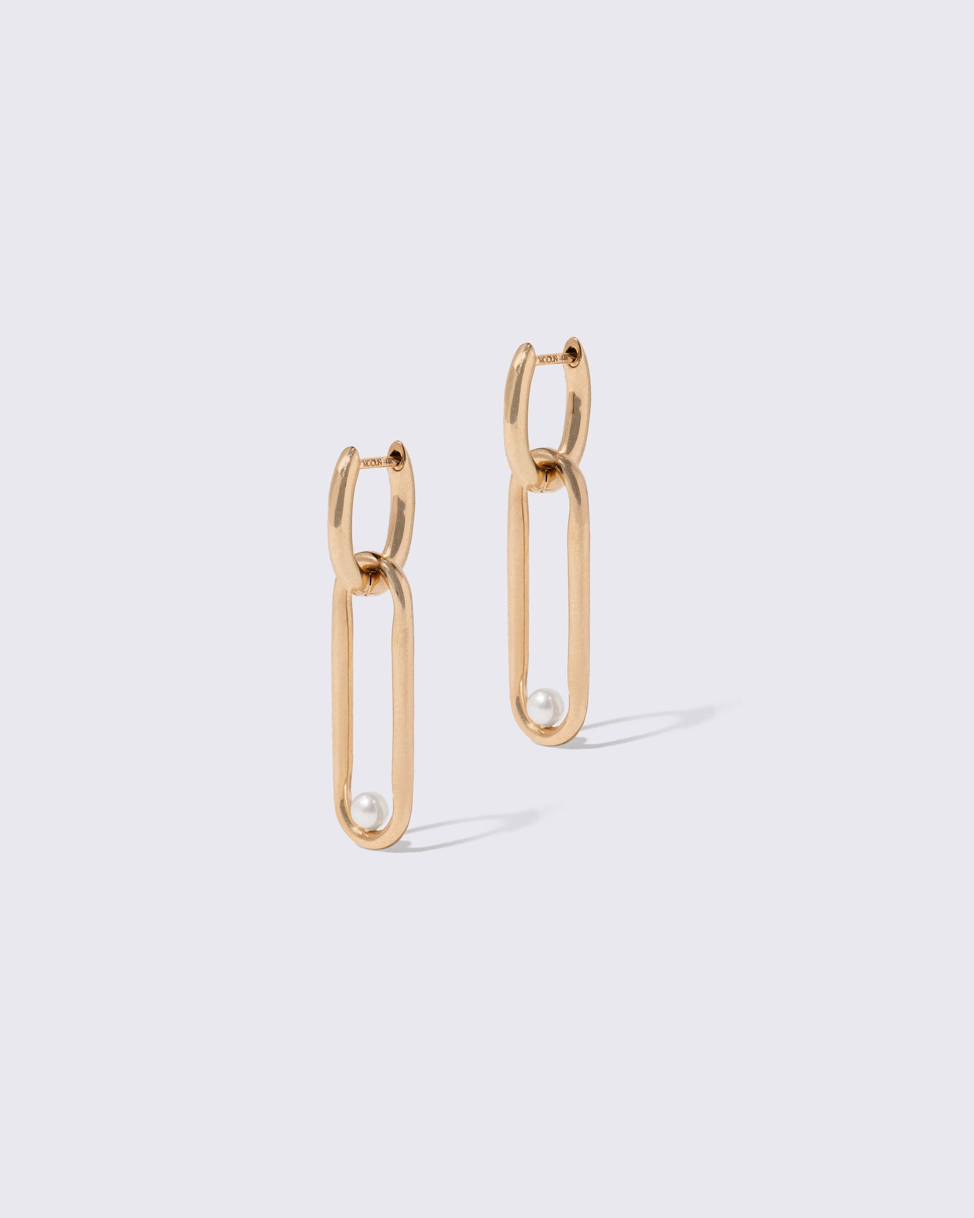 Pearl Link Huggie Hoop Earrings on light color background.