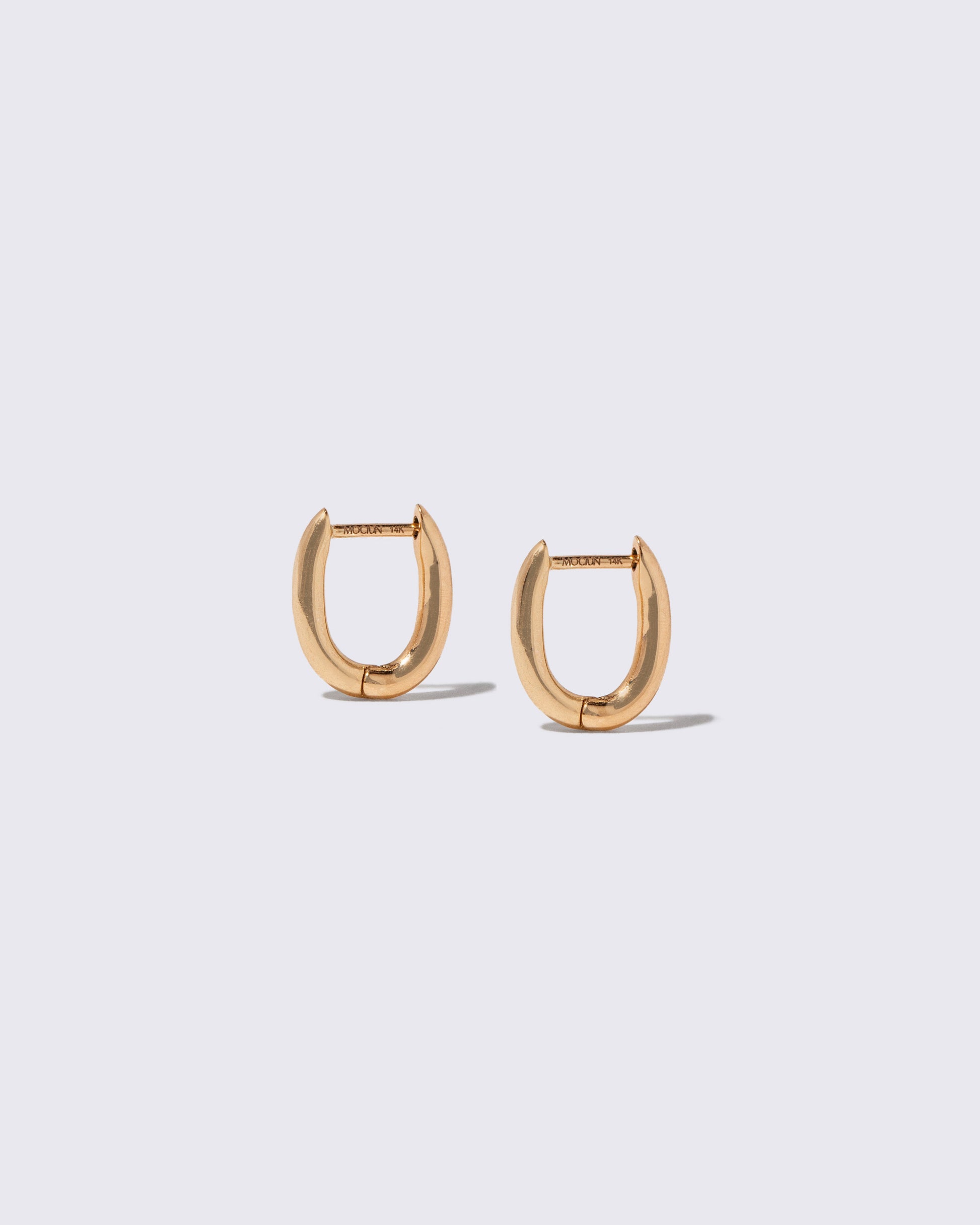Closeup details of the Styling Huggie Hoop Earrings on light color background.