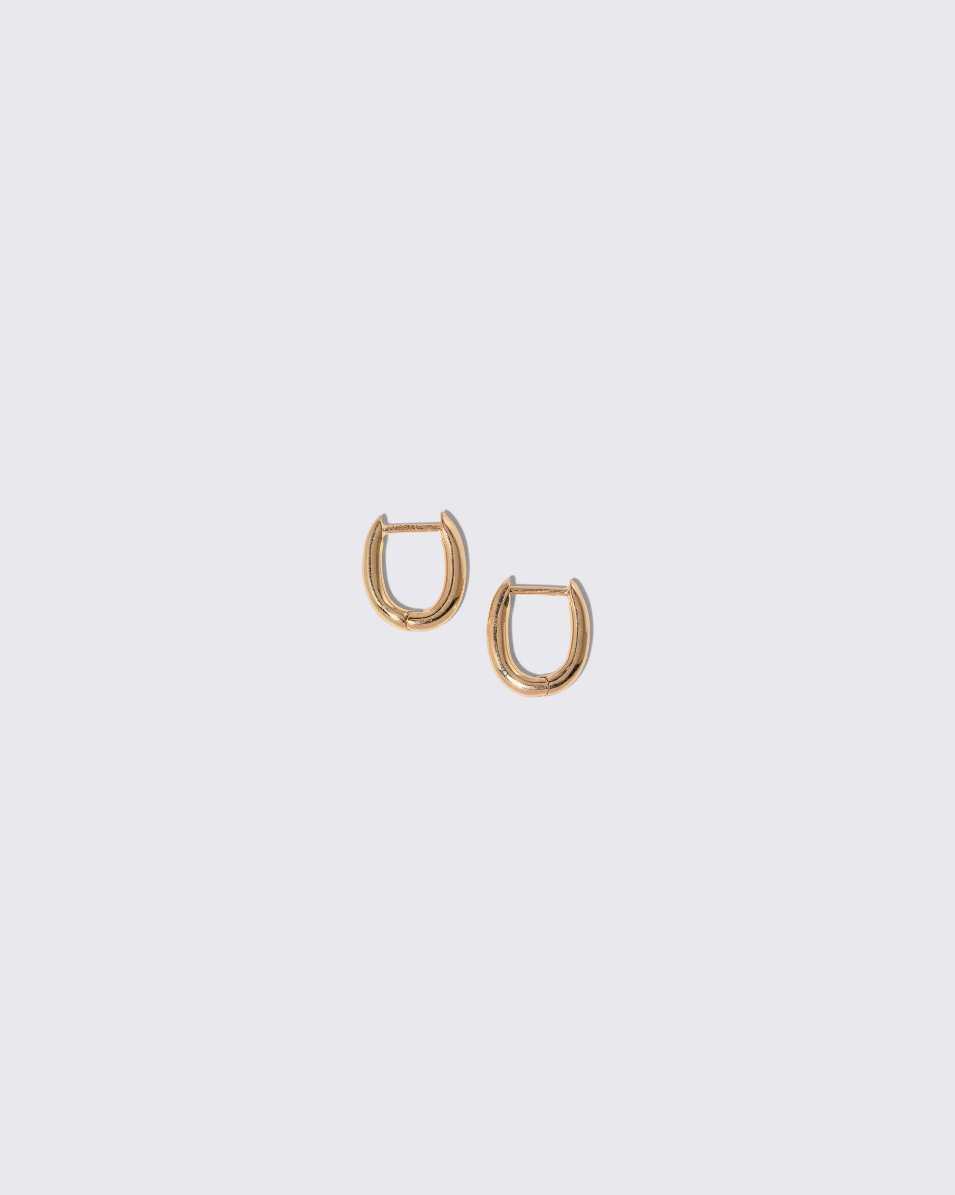 Styling Huggie Hoop Earrings on light color background.