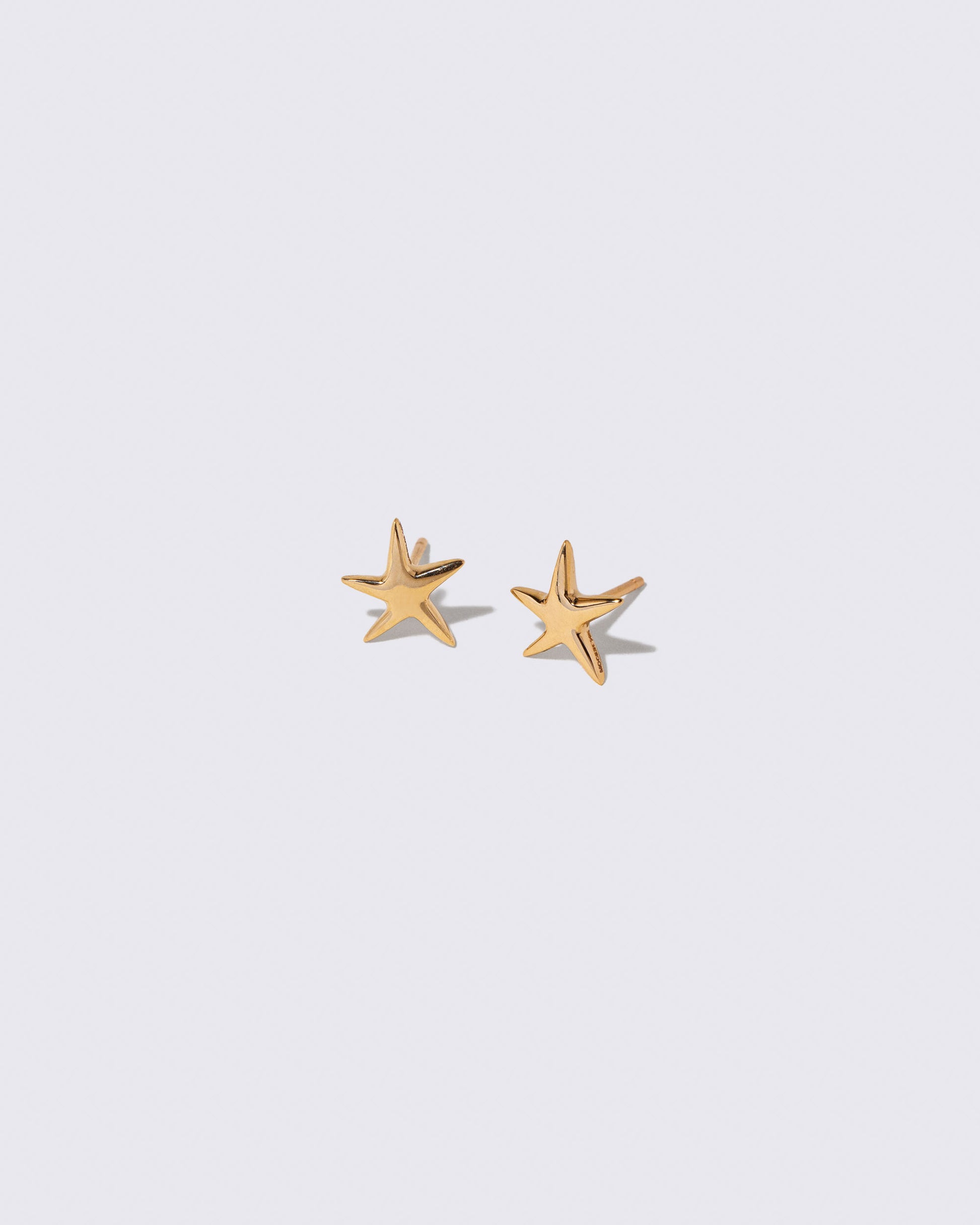 Gold Verve Five Point Star Stud Earrings on light color background.