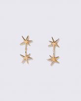 Gold Verve Star Drop Earrings on light color background.