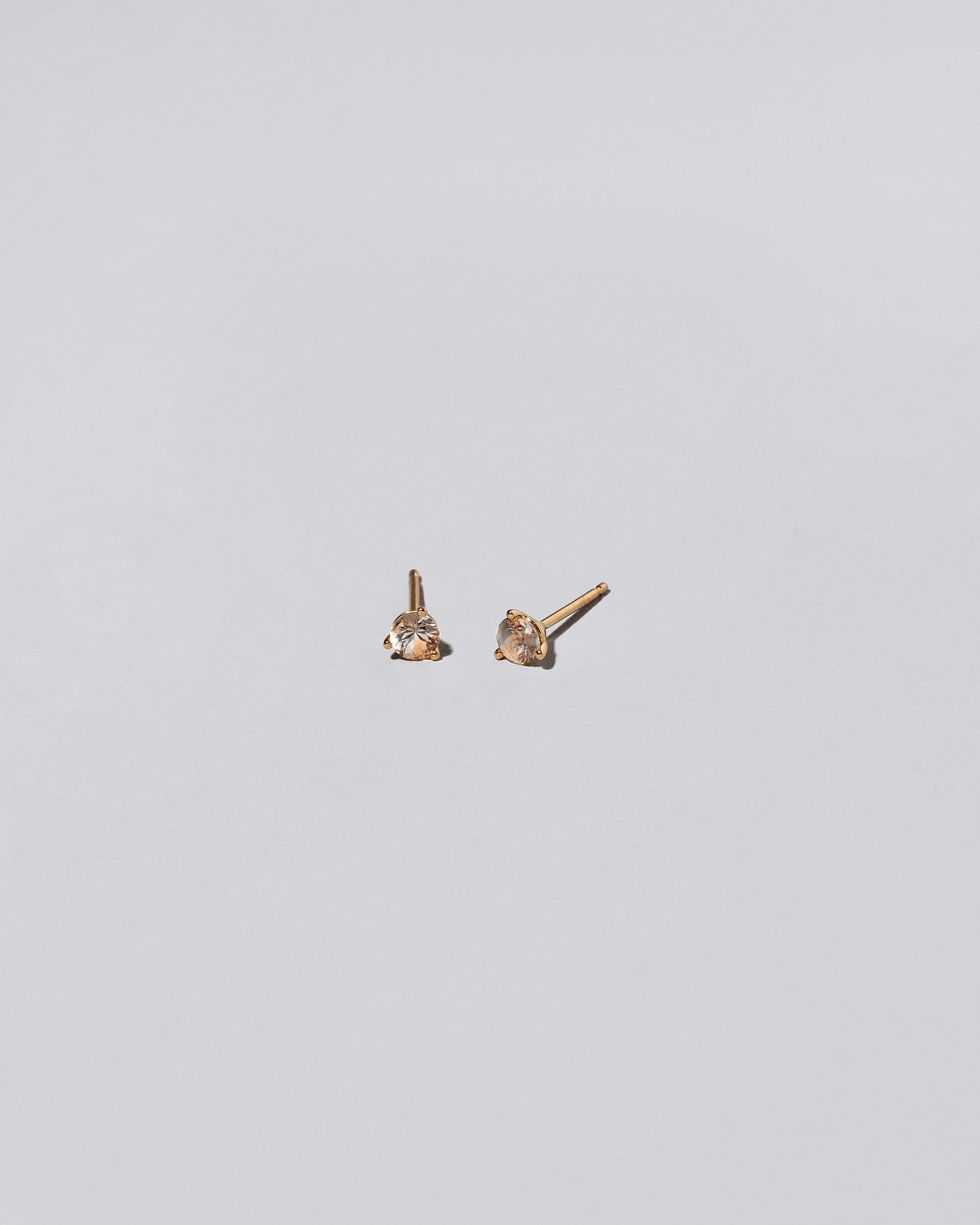 Peach Sapphire Martini Stud Earrings on light color background.