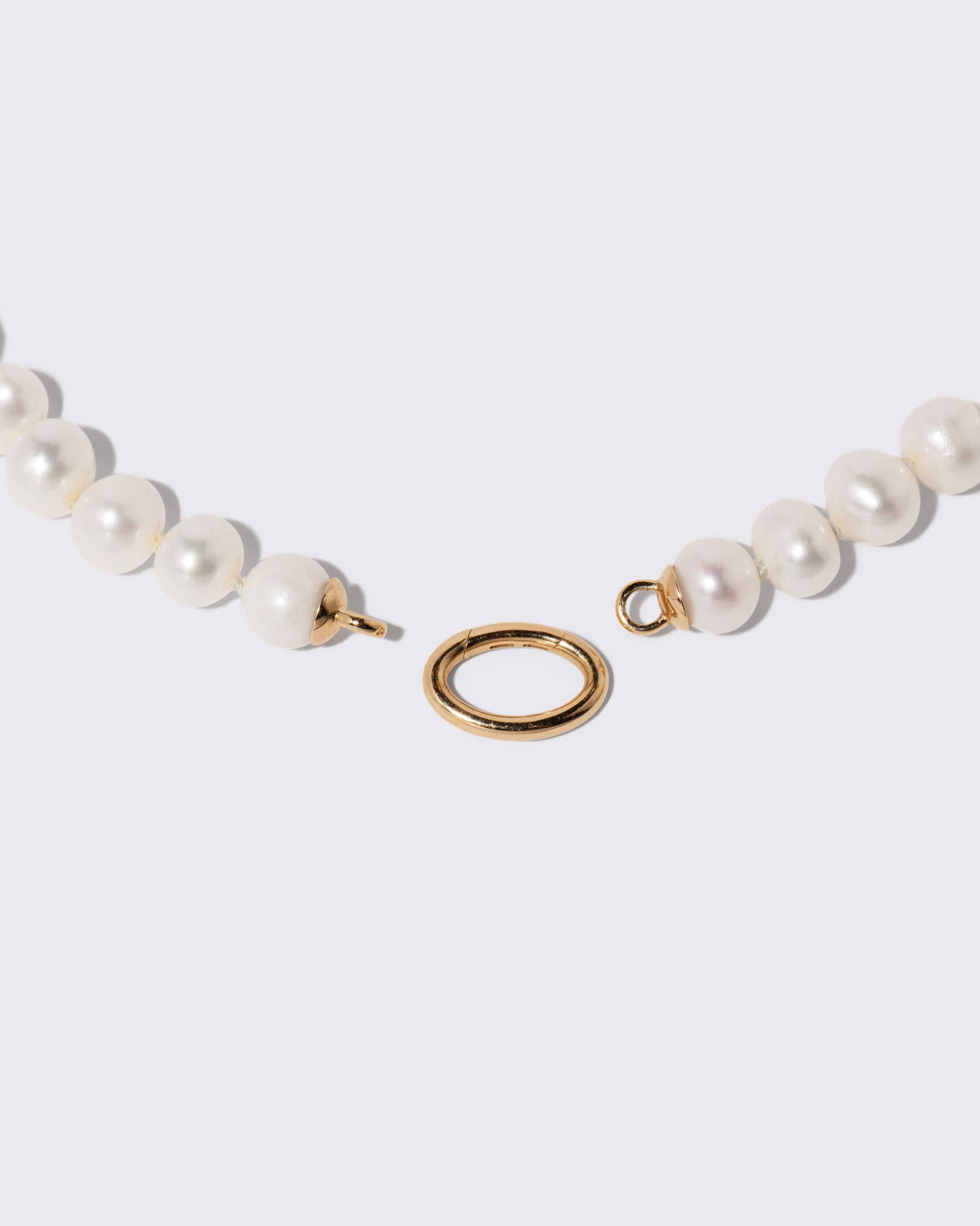Detail view of the detachable Mociun Long Oval Openable Link closure on the Gold Pearl Openable Link Necklace on light color background.