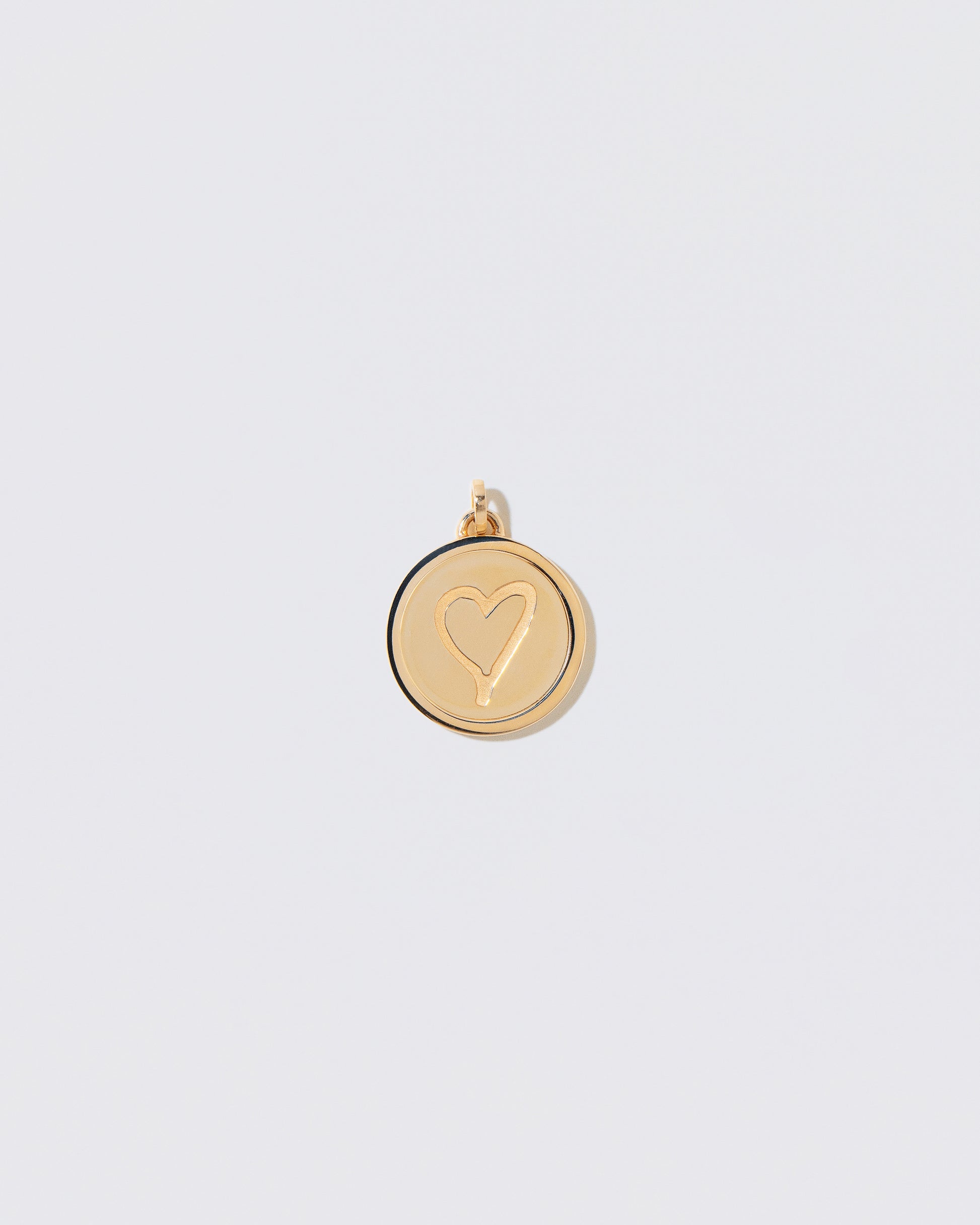 Finished Large Round Pendant Memento Pendant engraved with a heart shape on light color background.