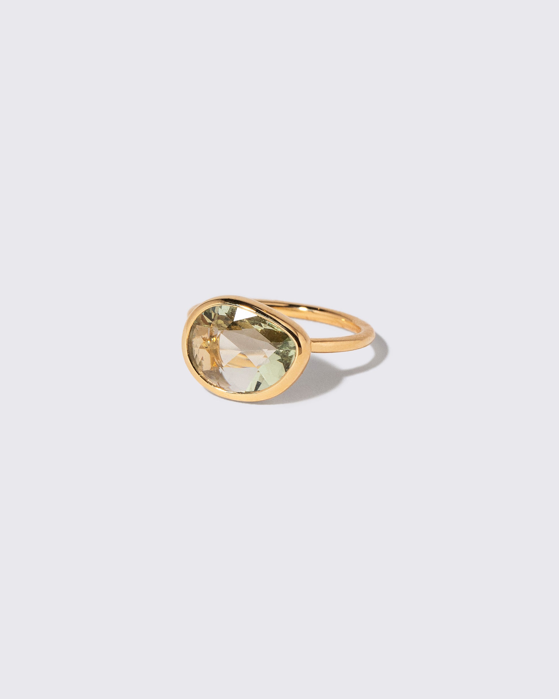 View from the side of the Green Sapphire Gusher Ring on light color background.