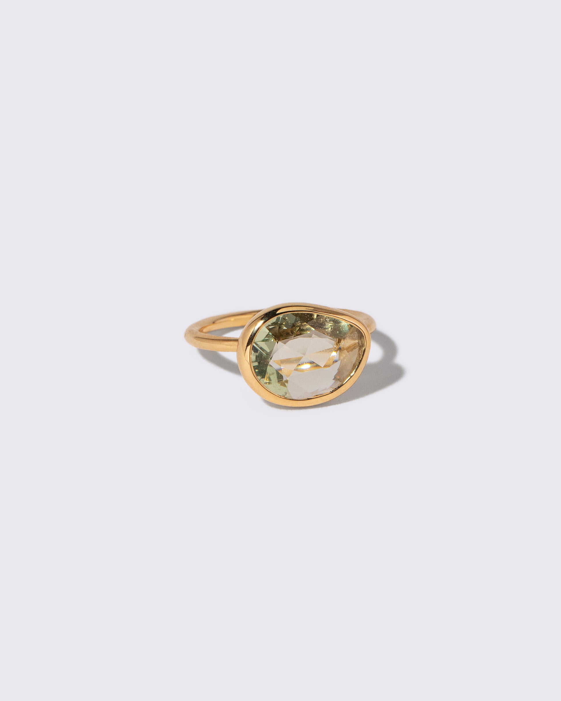 View from the side of the Green Sapphire Gusher Ring on light color background.