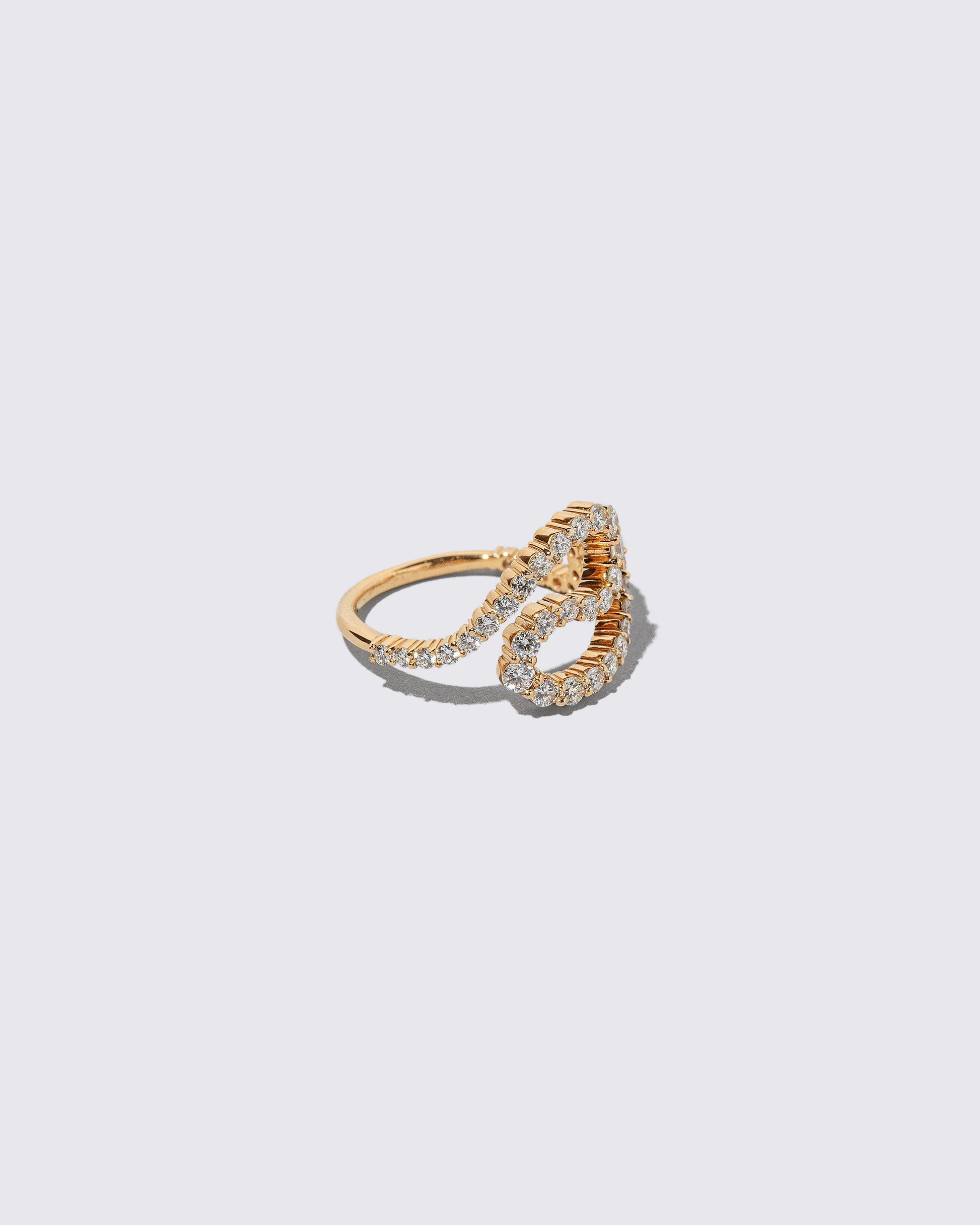 View from the side of the Gold White Diamond Tsunami Ring on light color background.