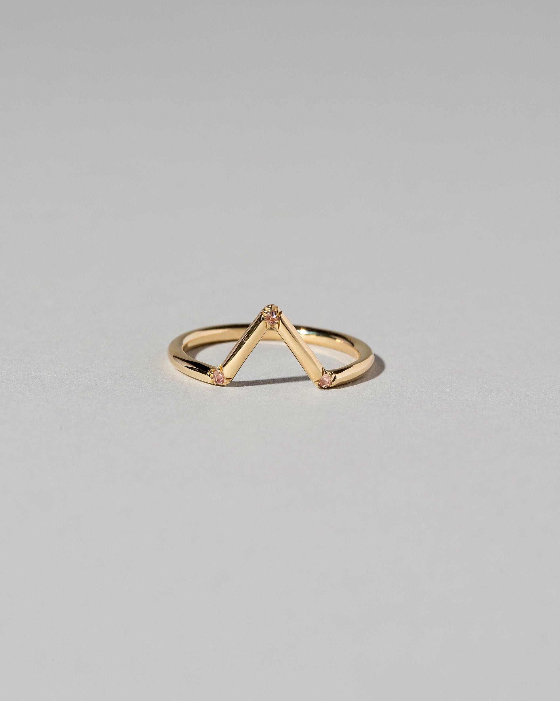 Gold Peach Sapphire Three Stone Triangle Band on light color background.