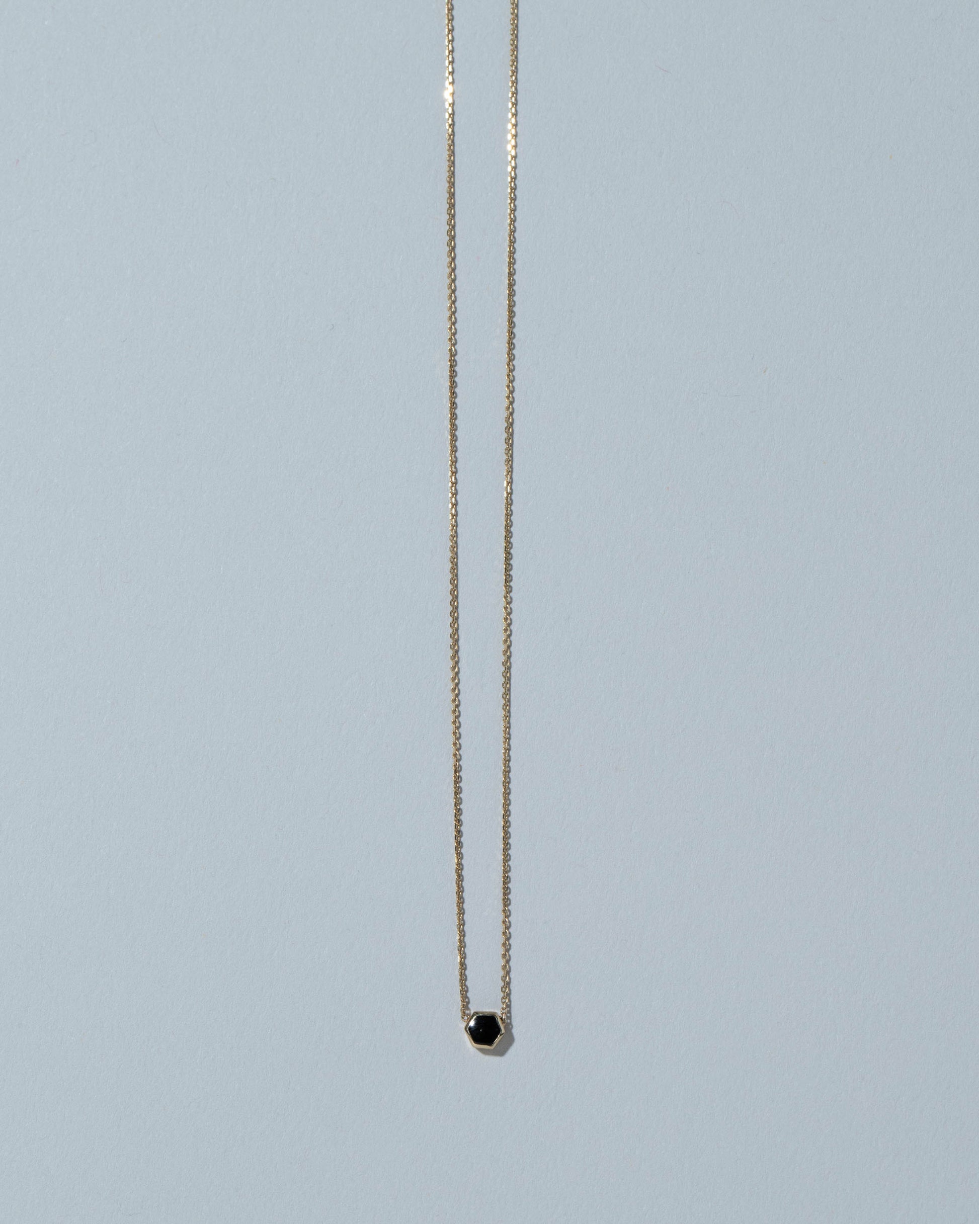 Black Spinel Hexagon Necklace on light color background.