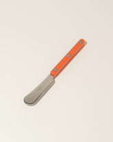 Sabre Paris Orange Butter Spreader on light color background.
