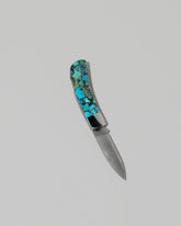 Santa Fe Stoneworks Kingmen Turquoise Lockback Knife on light color background.
