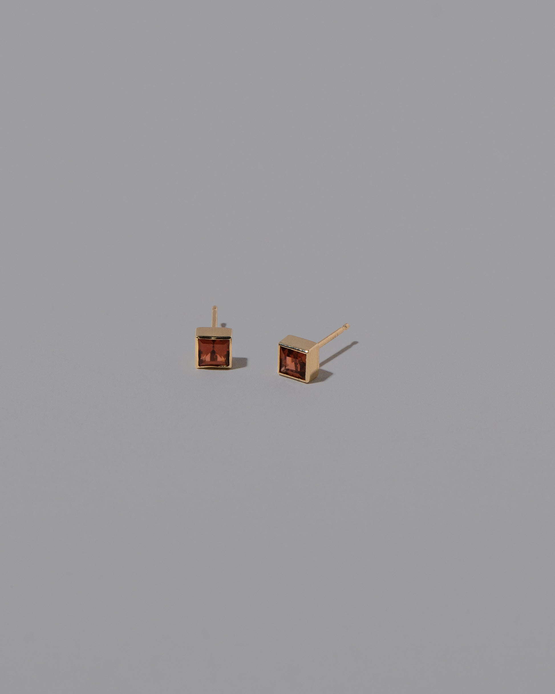 Grand Anthill Garnet Square Frame Stud Earrings on light color background.